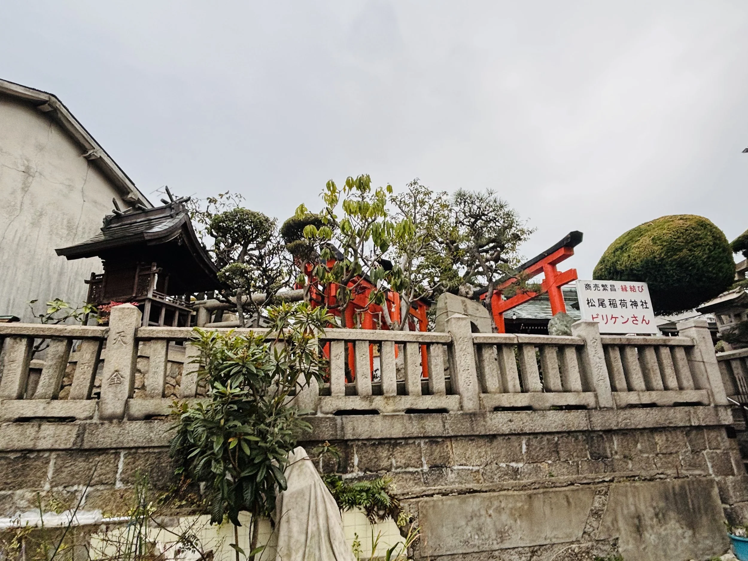 Kobe Higashidemachi Shrine in Kobe, Japan, a small neighborhood Shinto site with stone wall, greenery, and red torii gate