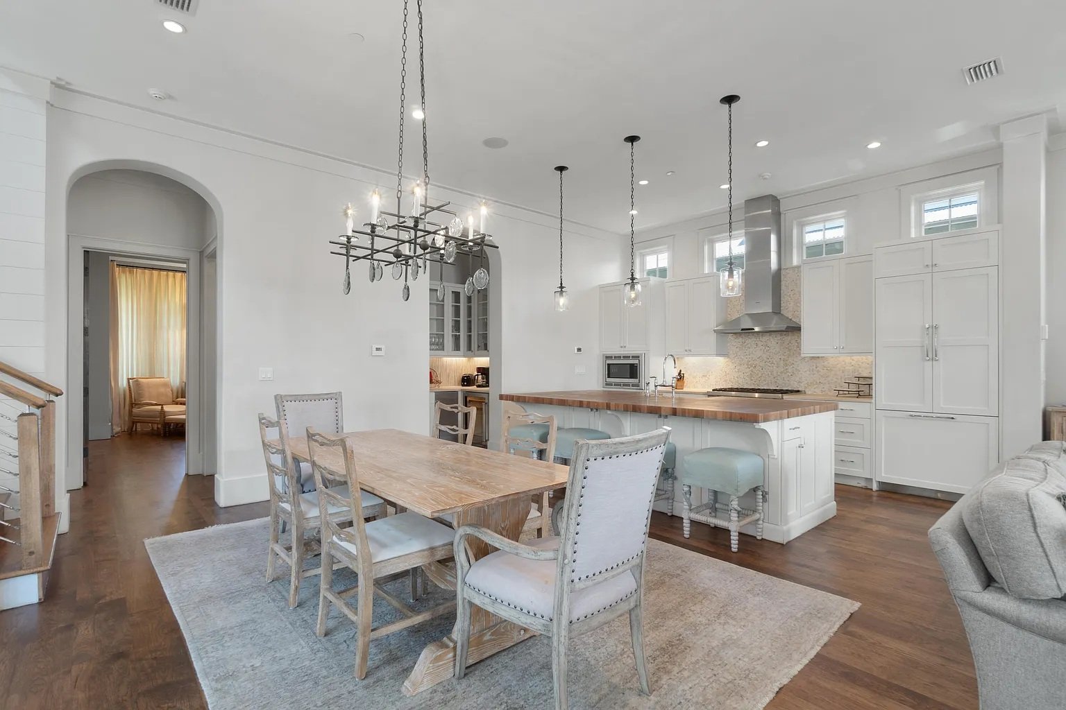 Open-concept dining and kitchen area with white cabinets, a wooden dining table, and a chandelier.