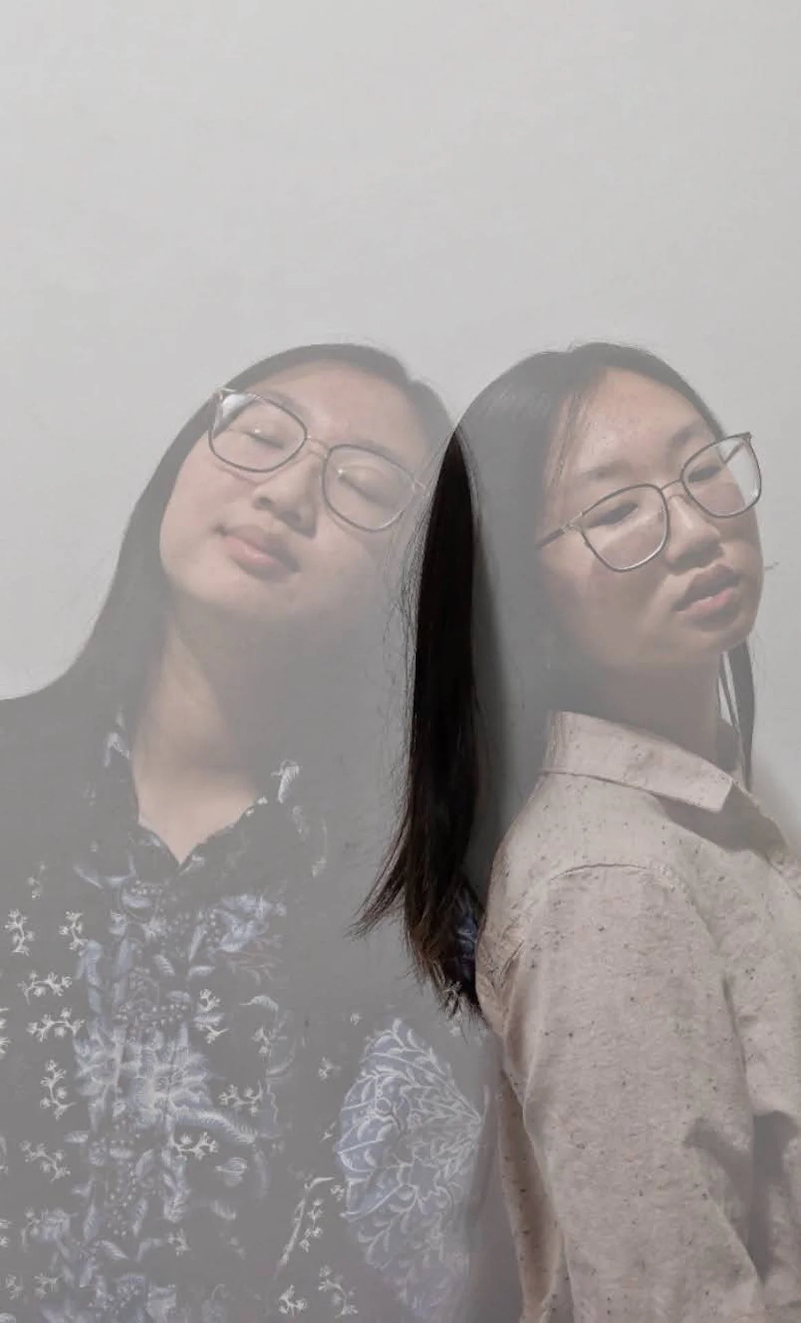 A mirror or reflective surface creates a double image of a woman with glasses and long dark hair, one side showing her face with eyes closed and the other with her eyes open and head slightly turned.