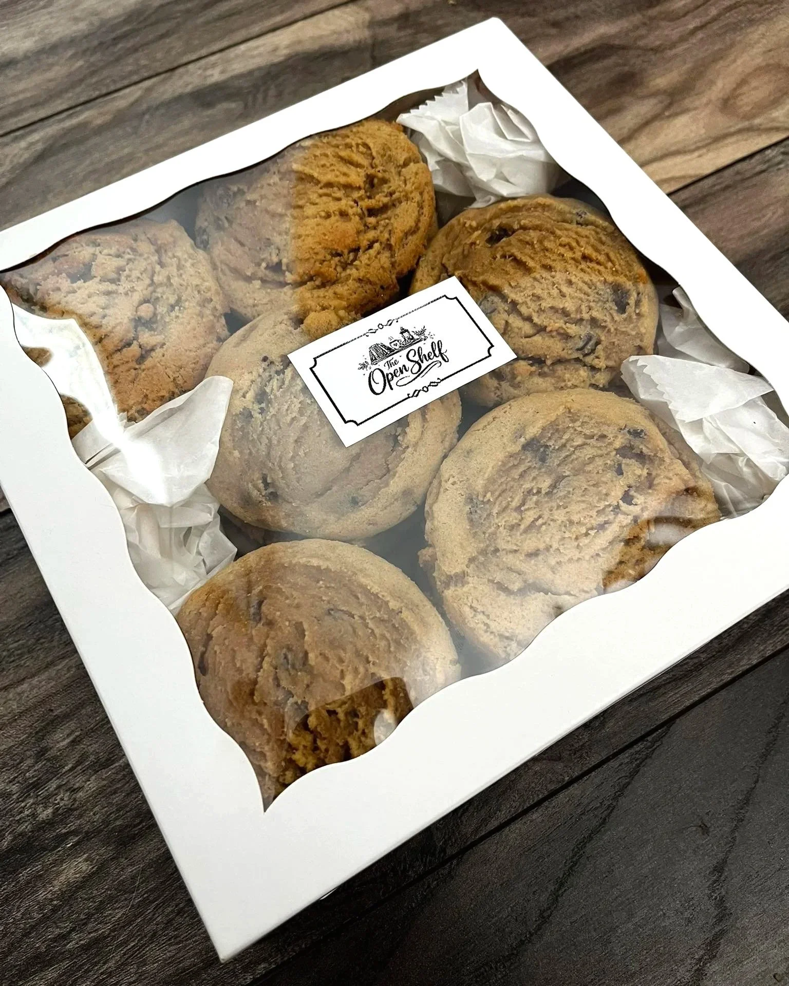 Box of chocolate chip cookies with a window on top, decorated with tissue paper and a label that says 'Open Shelf'.