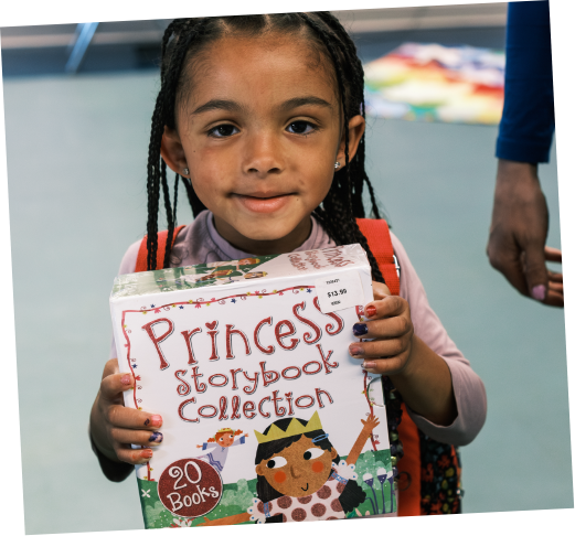 Young girl holding a book titled 'Princess Storybook Collection' at a store or library.