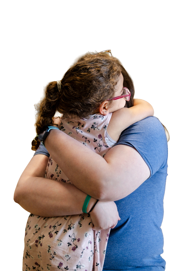 A woman hugging a young girl tightly, both embracing each other.