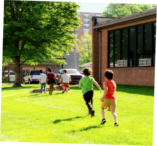 Children playing on a grassy lawn near a brick building on a sunny day.