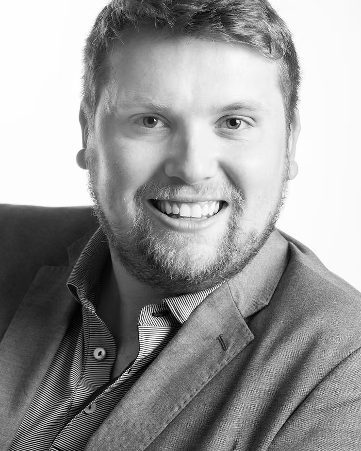 Black and white portrait of Chris Stibbs wearing a collared shirt.
