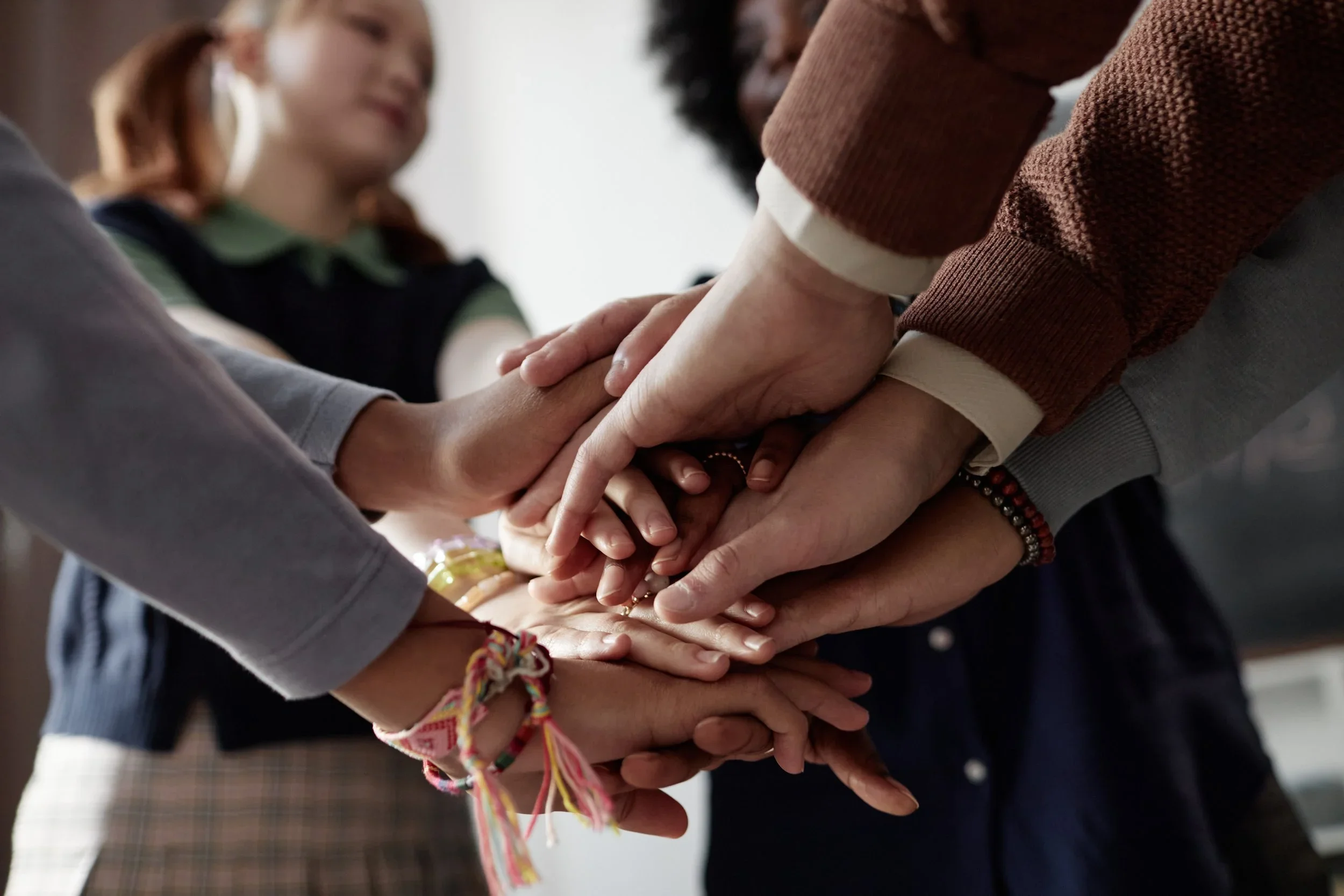Children placing their hands in the center of a circle — connection and teamwork