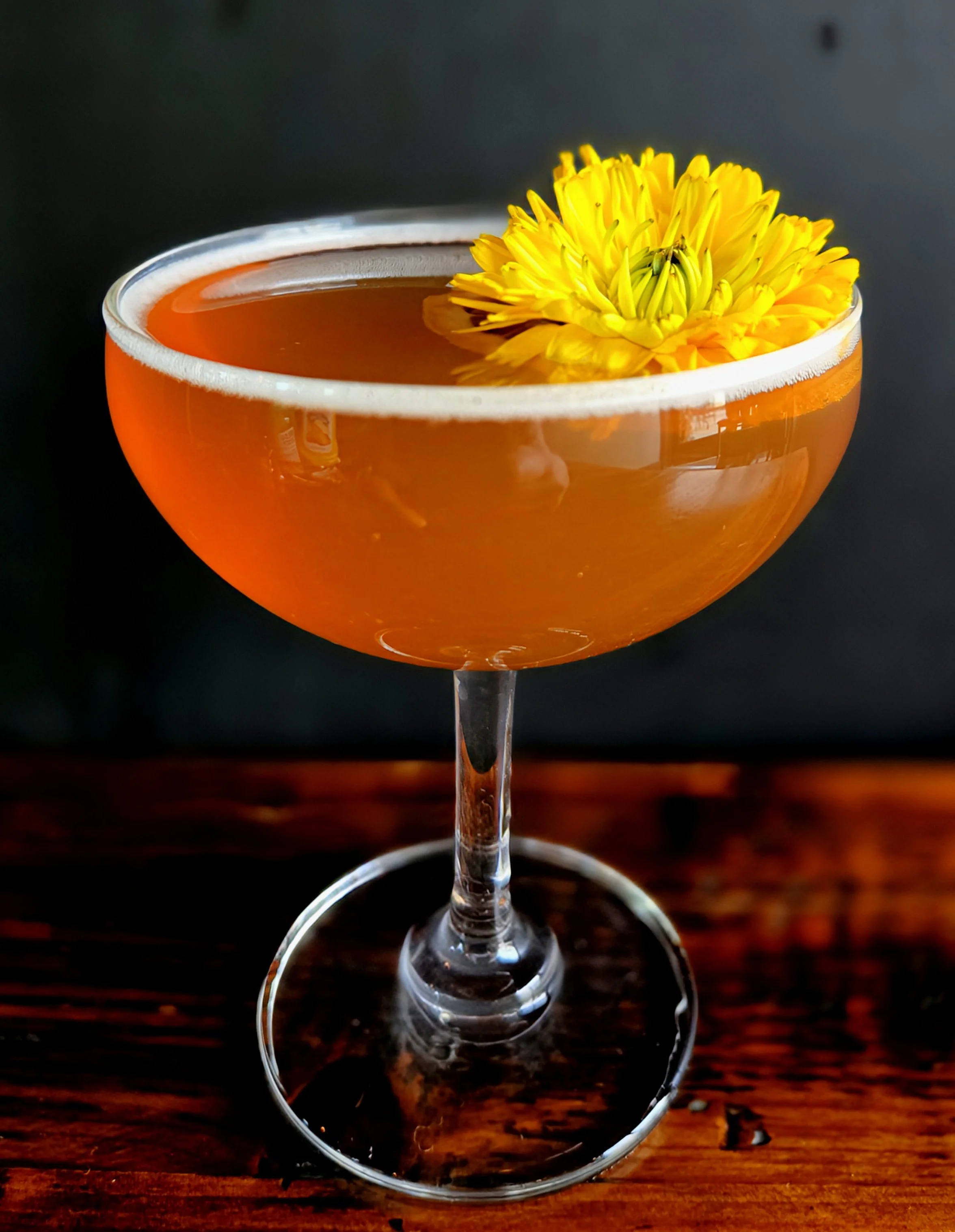 Portland Mobile bar service creates signature cocktail for wedding reception. Whiskey cocktail in coupe glass garnished with locally grown edible flower.