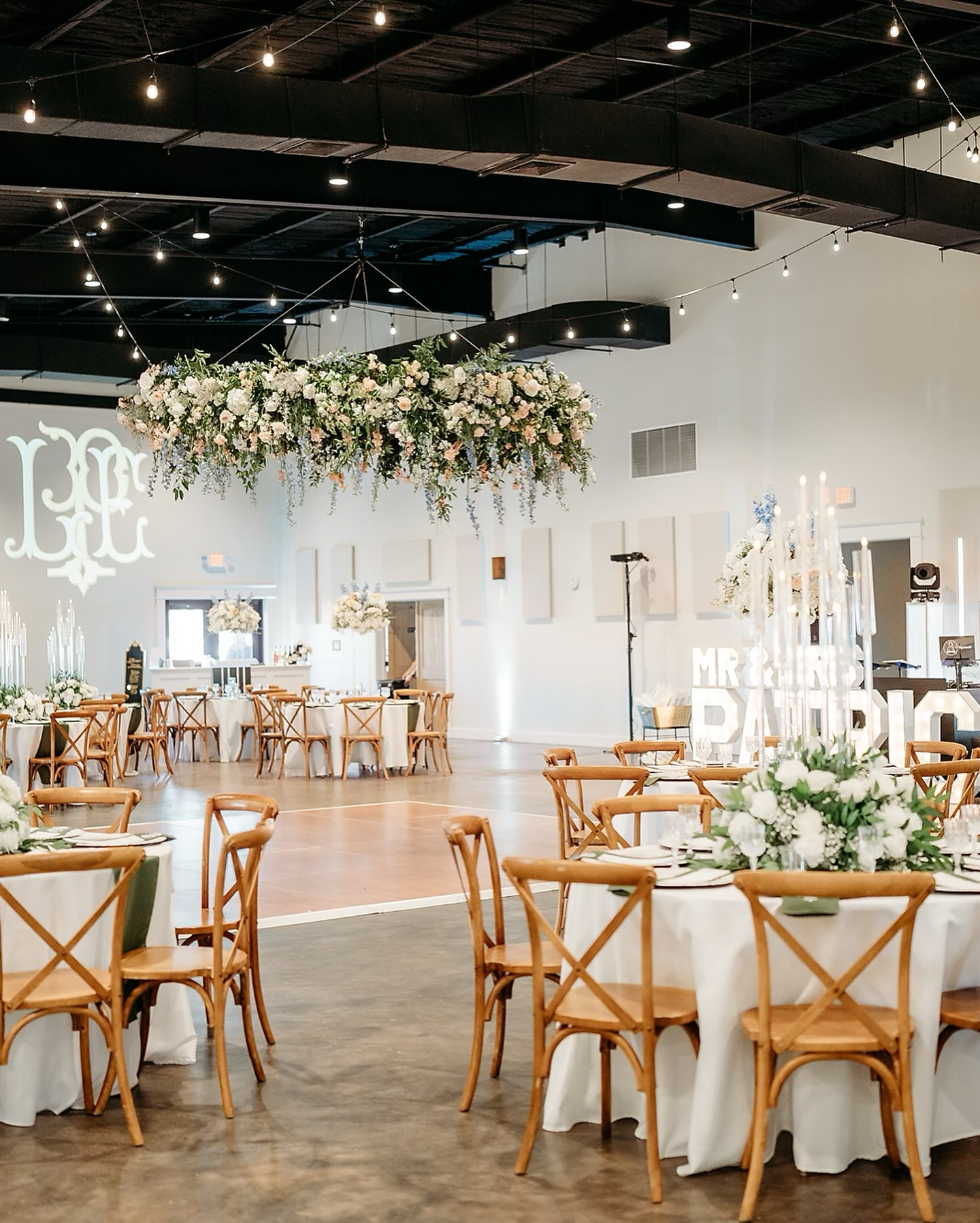 Elegant wedding reception hall decorated with floral centerpieces and a cascading flower arrangement hanging from the ceiling.