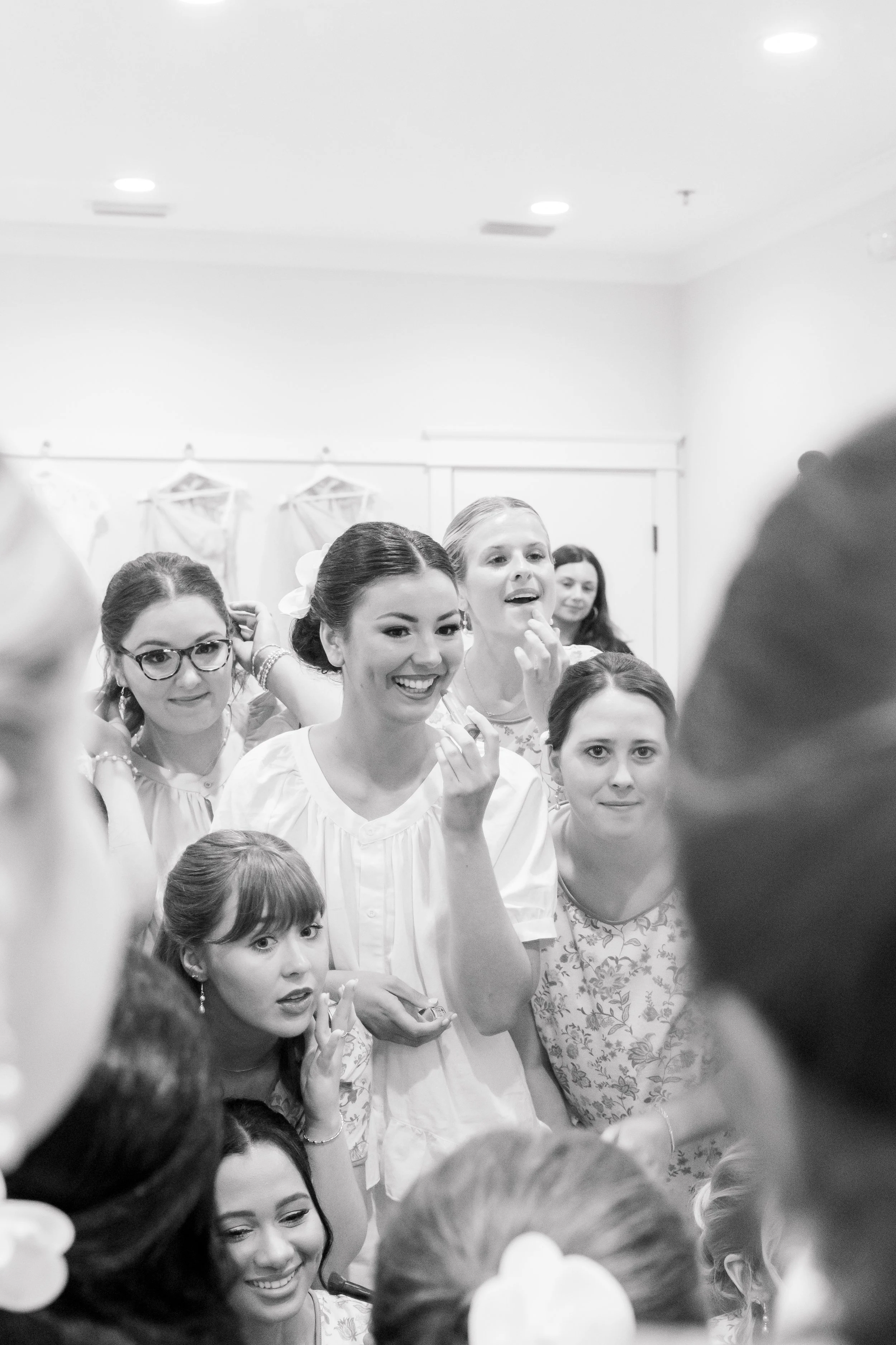 A group of women and girls gathered together, smiling and talking, in a bright room.