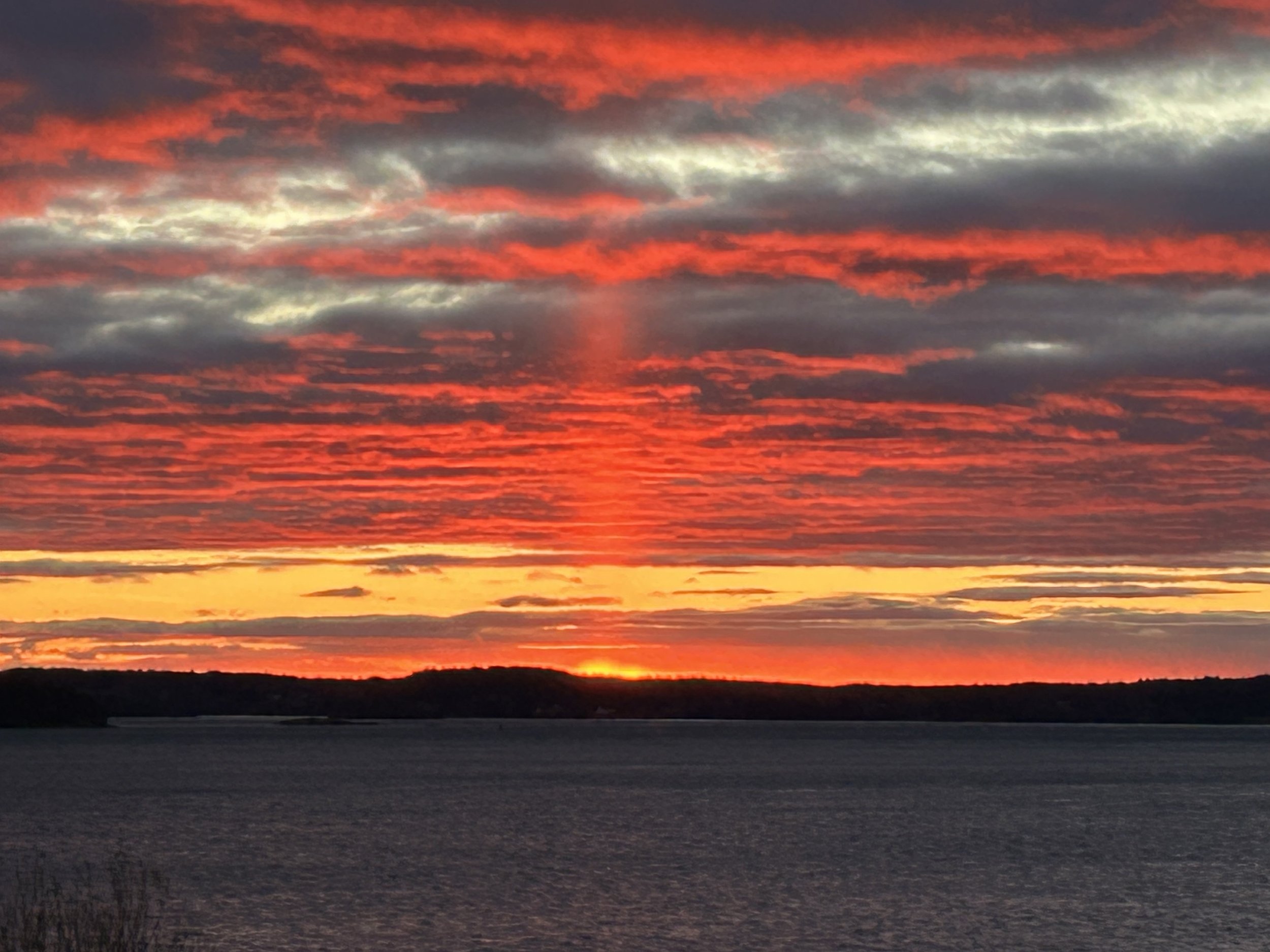 A vibrant sunset over a body of water with colorful clouds in the sky.