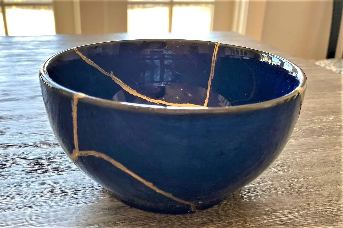 A ceramic bowl with a deep blue glaze and visible gold crackle pattern on a wooden table