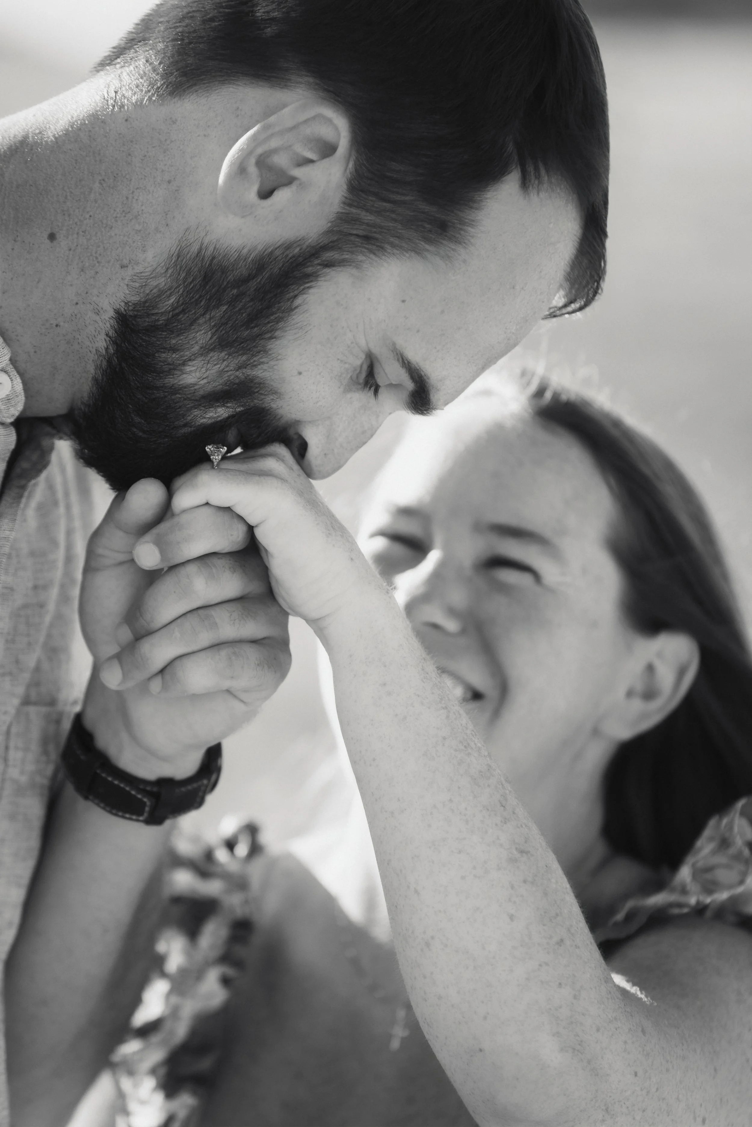A man with a beard and mustache kneels with his eyes closed, holding hands with a woman who is smiling with her eyes closed.