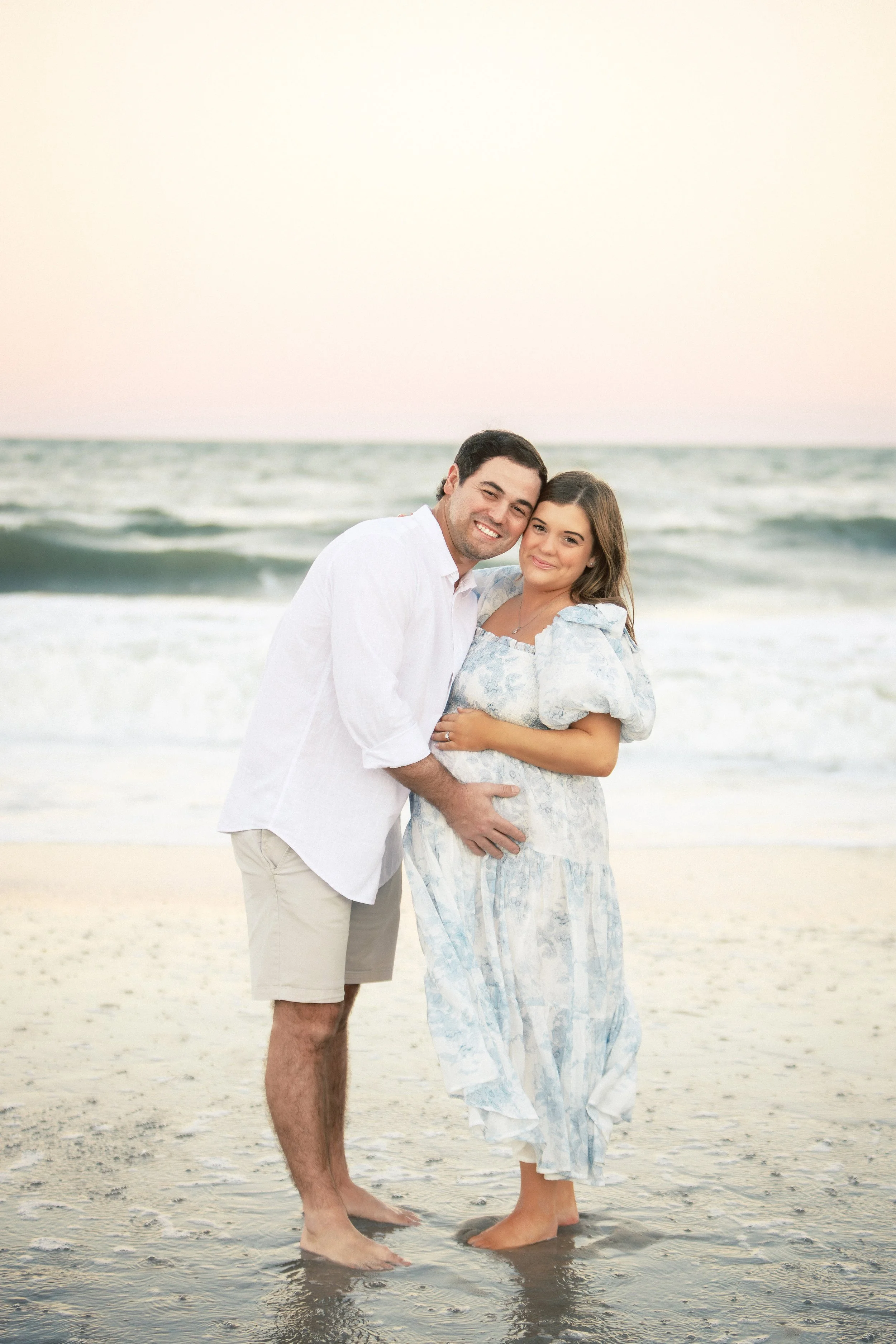 A smiling man and woman standing on a beach with the ocean in the background. Photographer Amelia Island, Jacksonville, St Augustine, St Simons Island, Savannah photographer