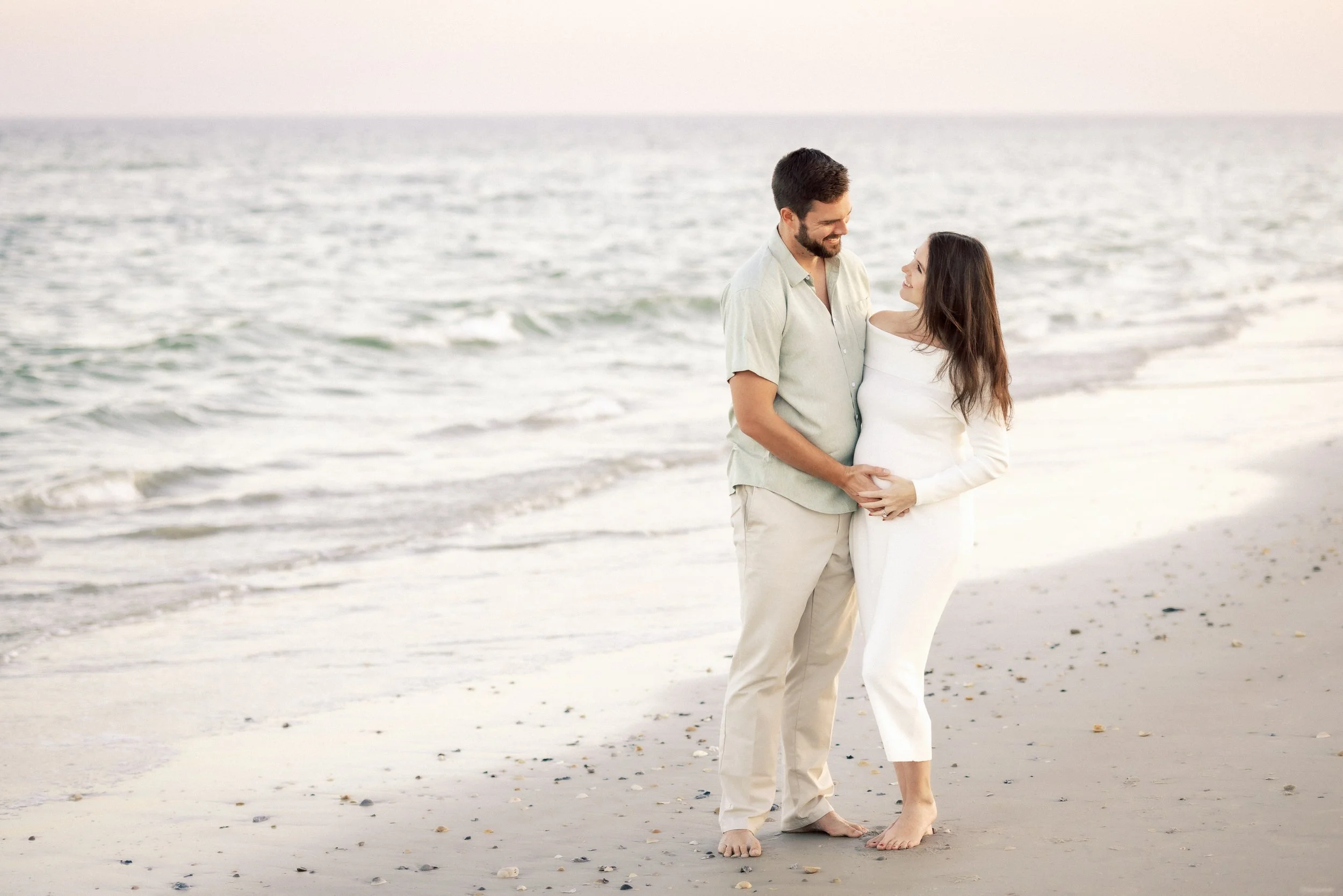 A couple stands together on a beach, gazing at each other. Photographer Amelia Island, Jacksonville, St Augustine, St Simons Island, Savannah photographer
