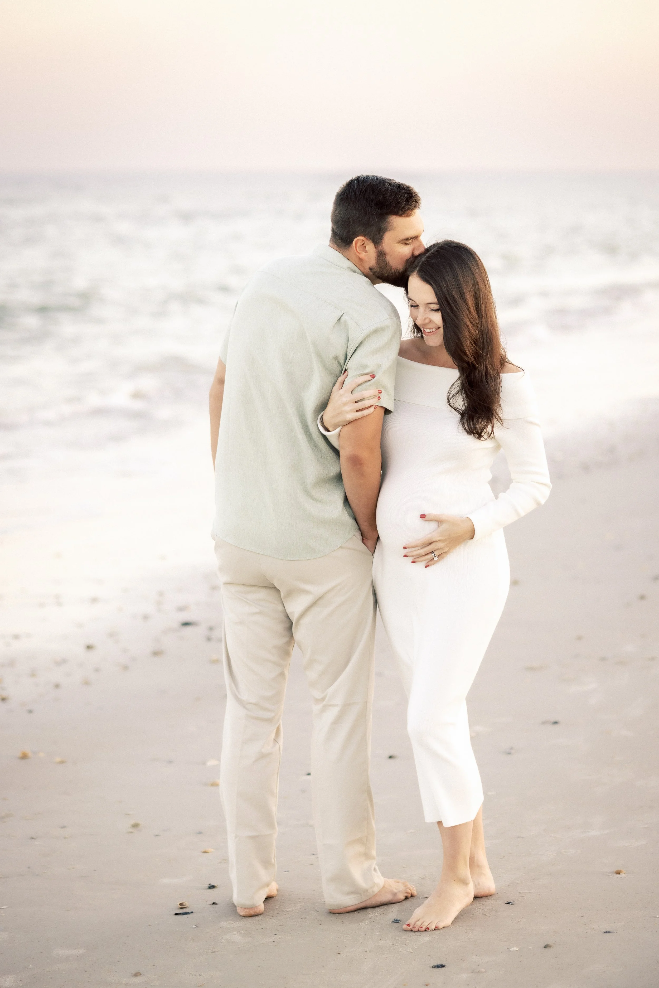 A man and woman embracing on the beach, with only their feet and legs visible, as the man kisses the top of the woman's head, Photographer Amelia Island, Jacksonville, St Augustine, St Simons Island, Savannah photographer