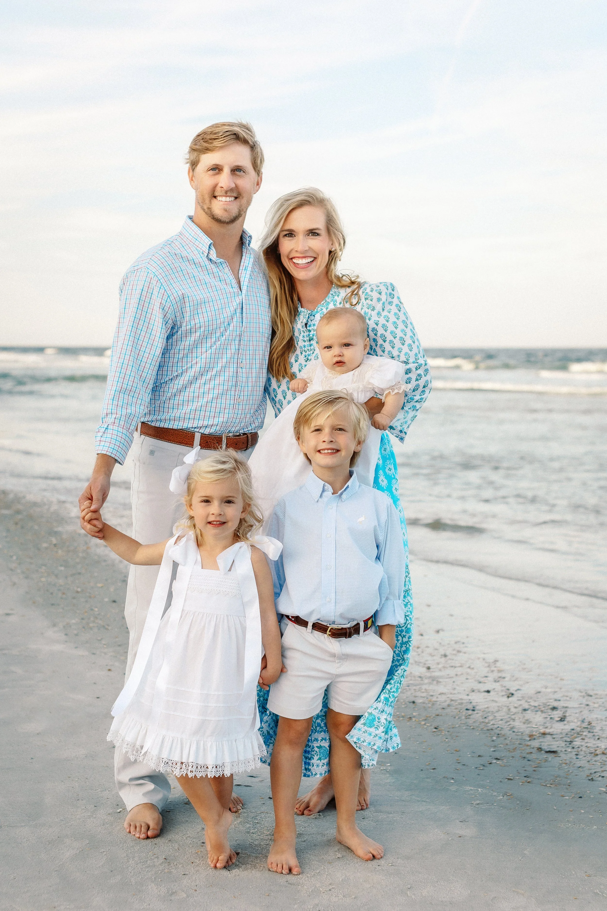 A family of six on the beach, smiling and holding hands, with ocean waves in the background. Photographer Amelia Island, Jacksonville, St Augustine, St Simons Island, Savannah photographer