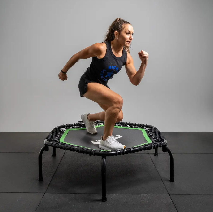 A woman jumping on a mini trampoline in a gym or fitness setting.