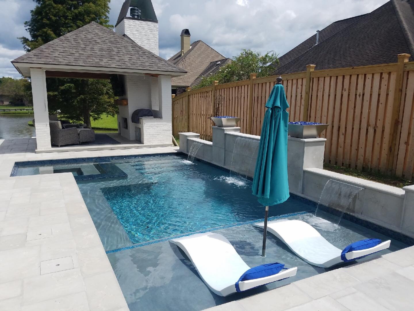 Geometric custom pool with waterfall and tanning ledge in Baton Rouge by Gulf South Pools & Outdoors.