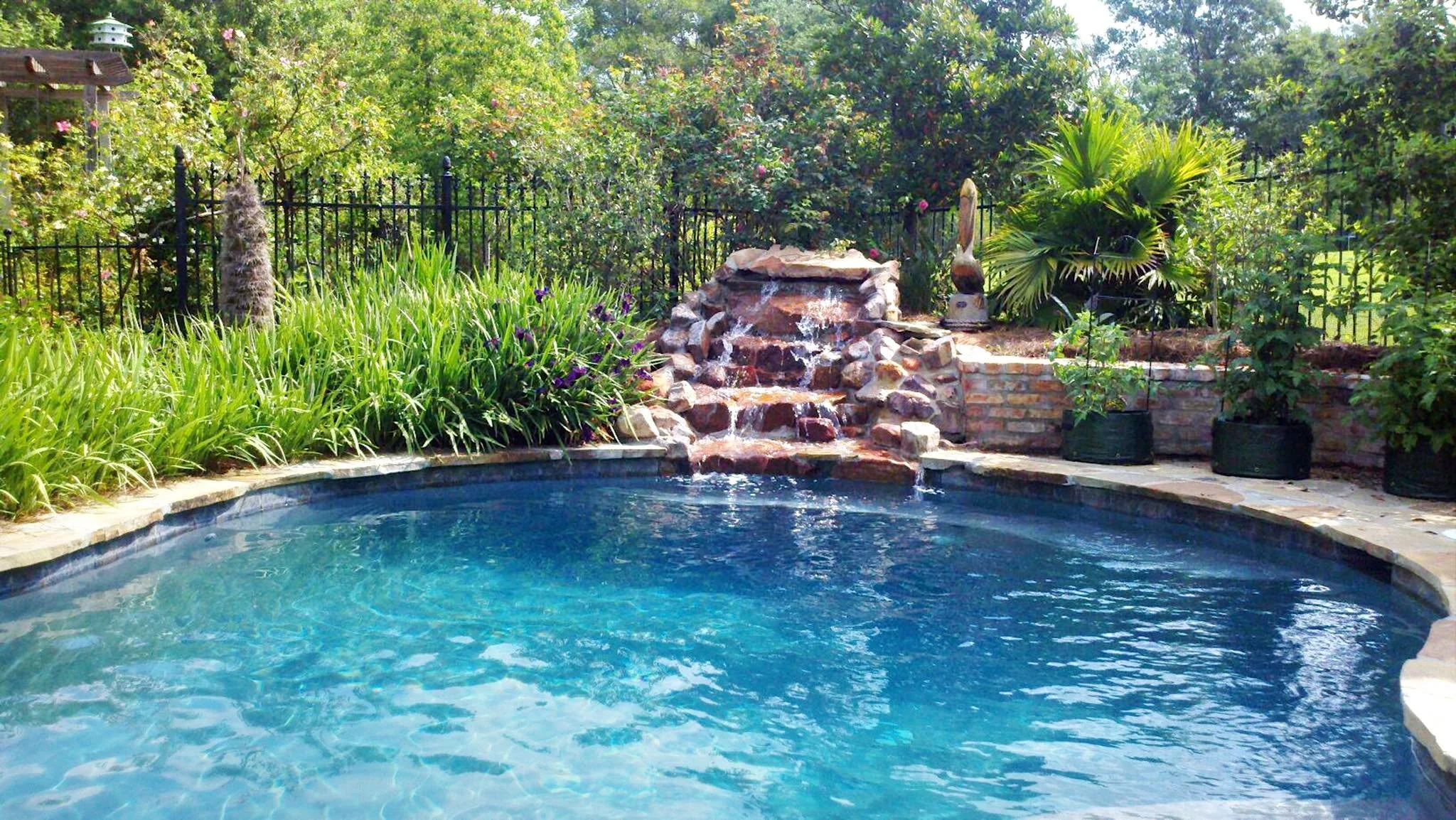 Custom-designed freeform residential pool with rock waterfall in Baton Rouge built by Gulf South Pools & Outdoors.