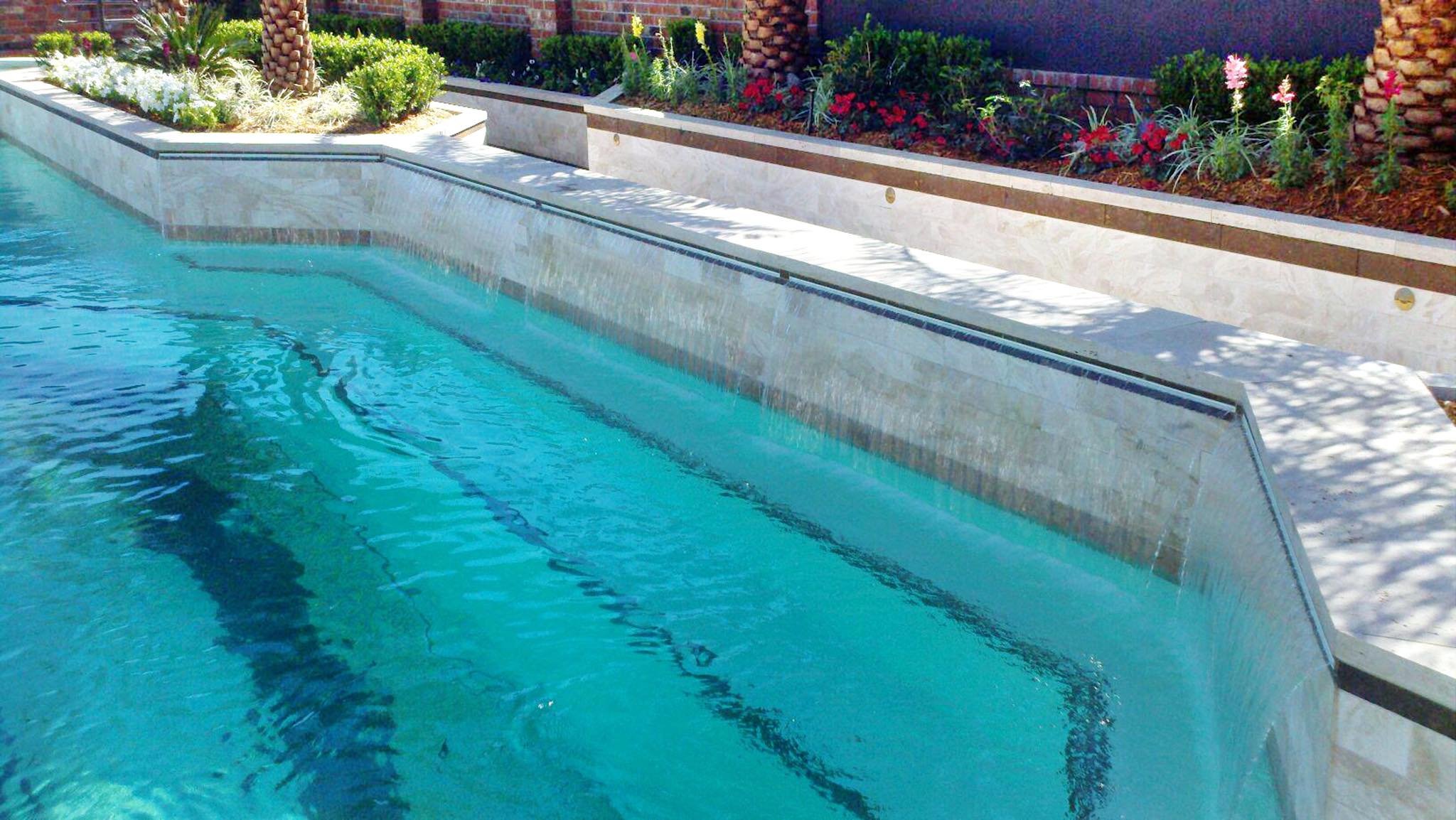 Custom-designed geometric residential pool with waterfall and hot tub in Baton Rouge built by Gulf South Pools & Outdoors.