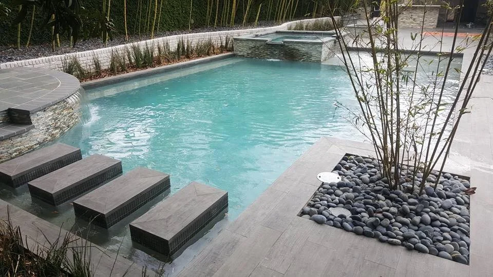 Custom-designed geometric residential pool with tanning ledge and hot tub in Baton Rouge built by Gulf South Pools & Outdoors.