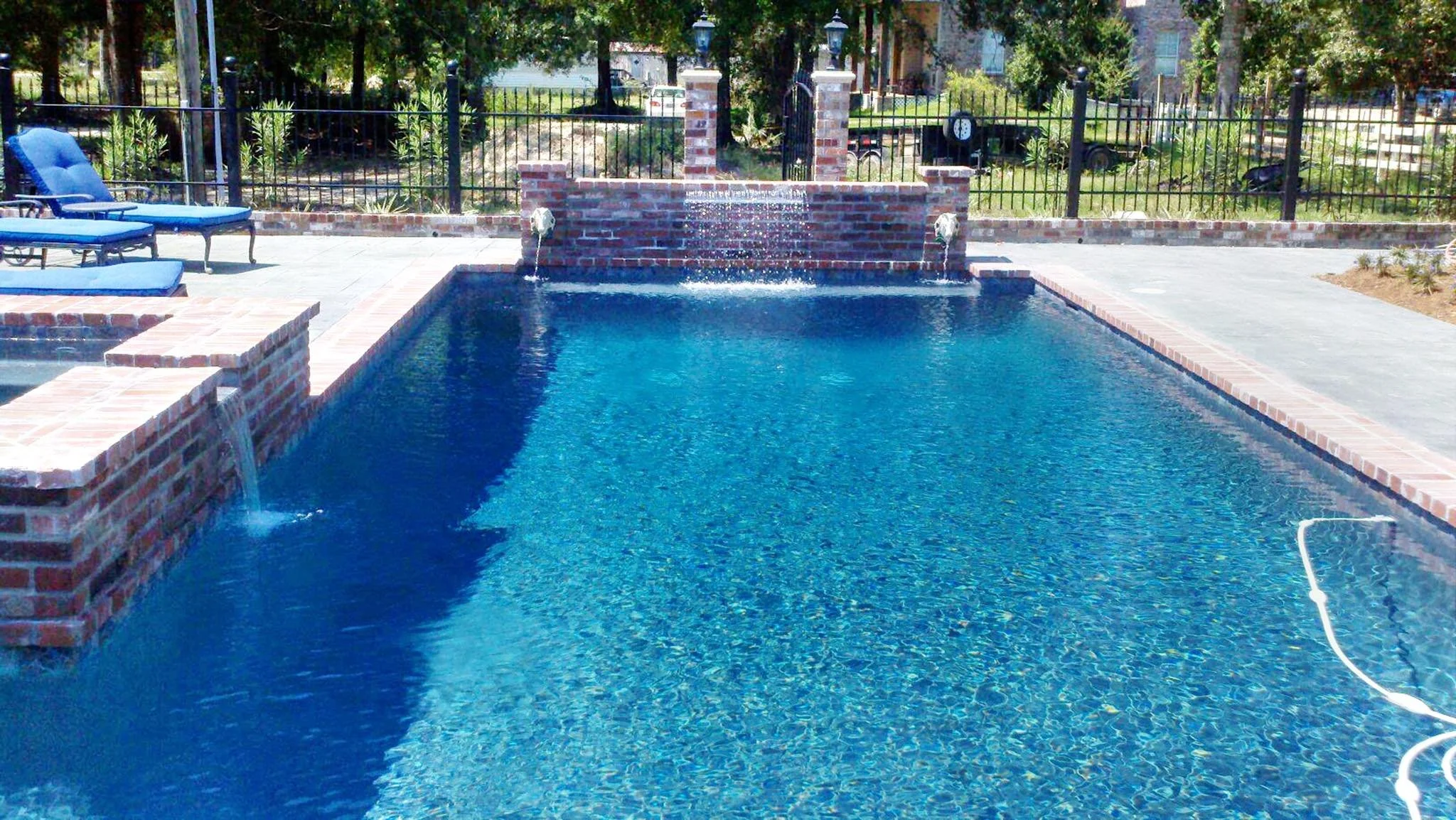 Custom-designed geometric residential pool with waterfall and hot tub in Baton Rouge built by Gulf South Pools & Outdoors.