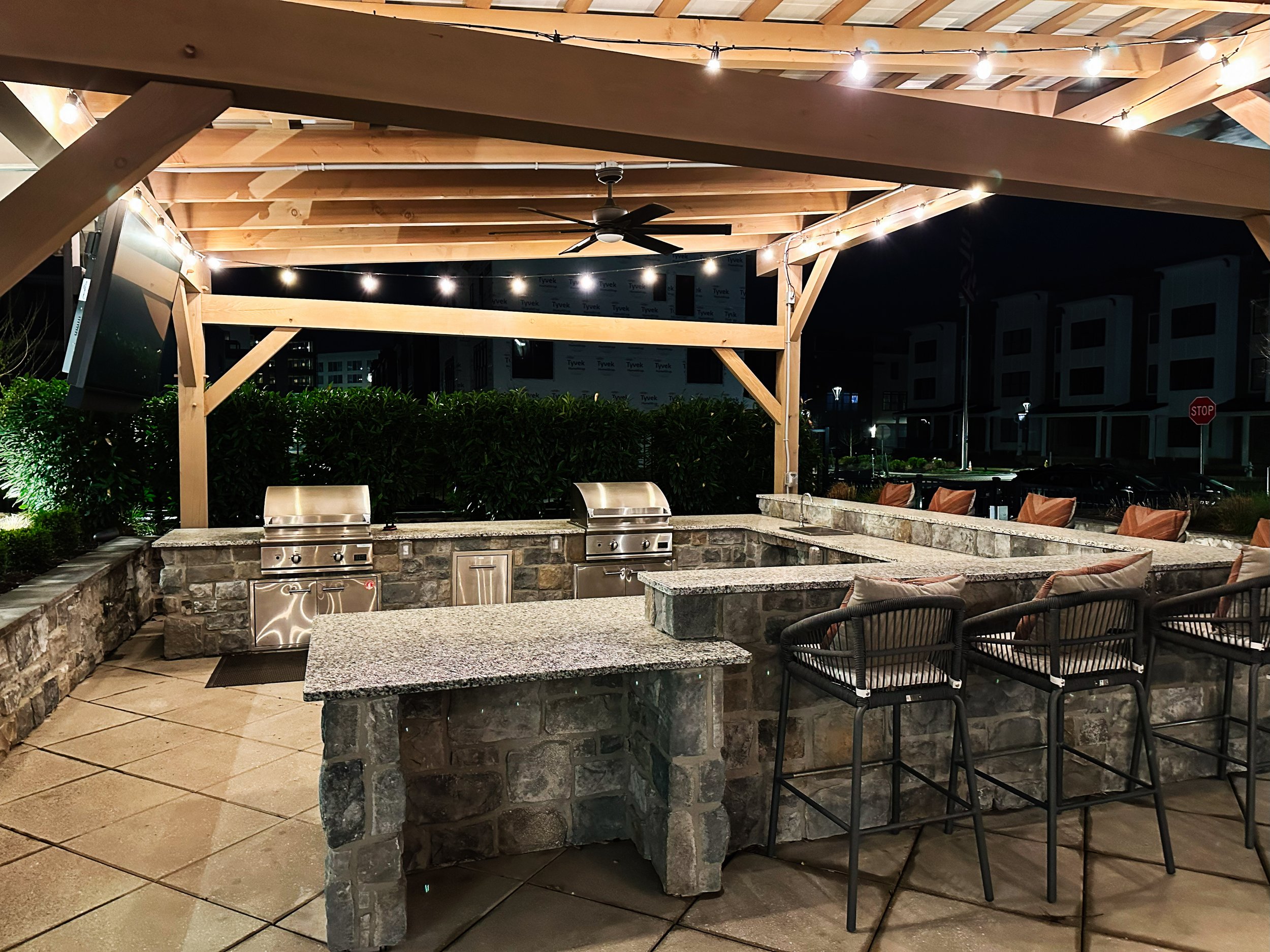 Luxury U-shaped outdoor kitchen and bar in Baton Rouge featuring a covered pergola and expansive layout for seamless gatherings and year-round outdoor living.