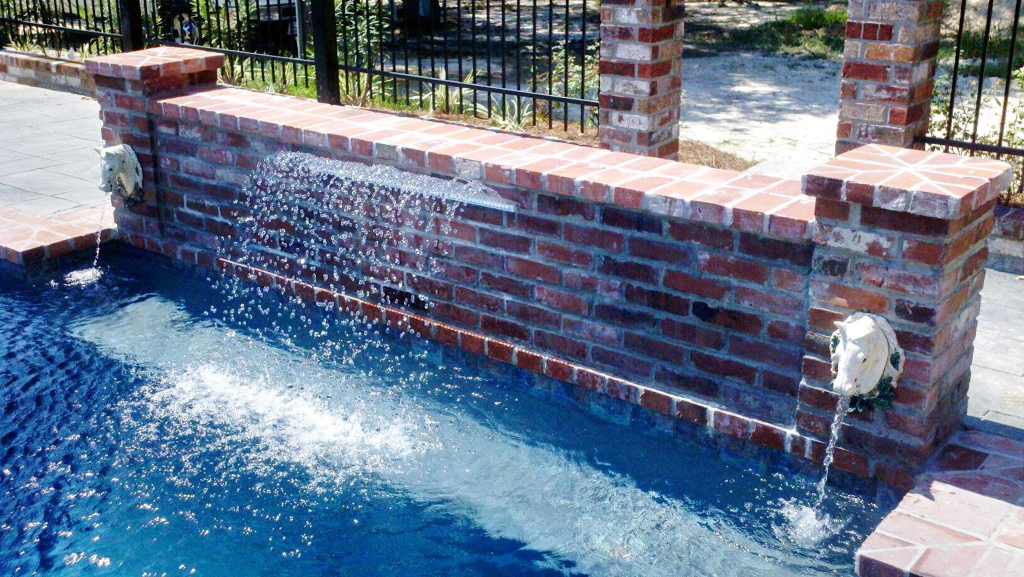 Custom-designed geometric residential pool with waterfall and hot tub in Baton Rouge built by Gulf South Pools & Outdoors.