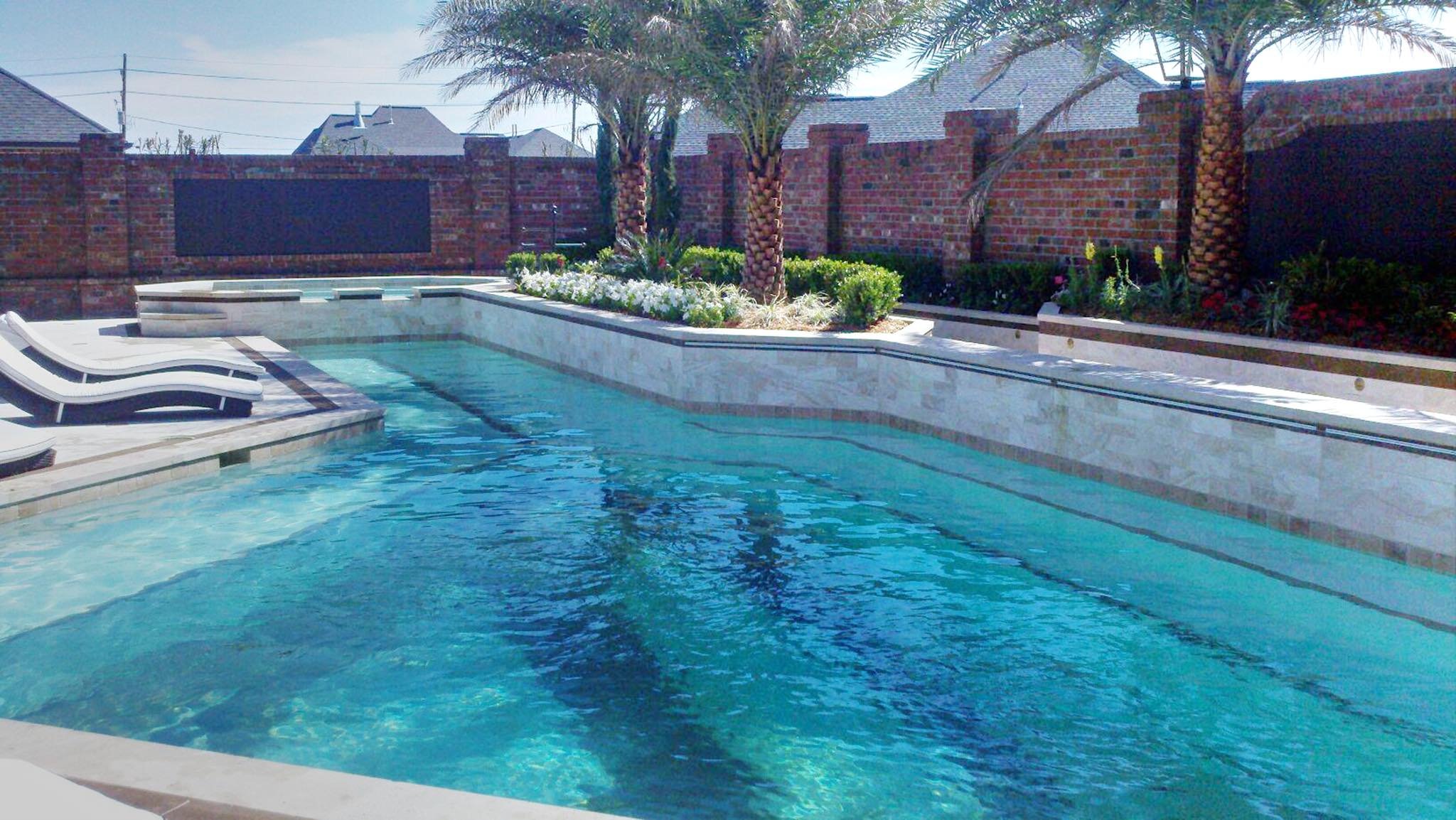 Custom-designed geometric residential pool with waterfall and hot tub in Baton Rouge built by Gulf South Pools & Outdoors.