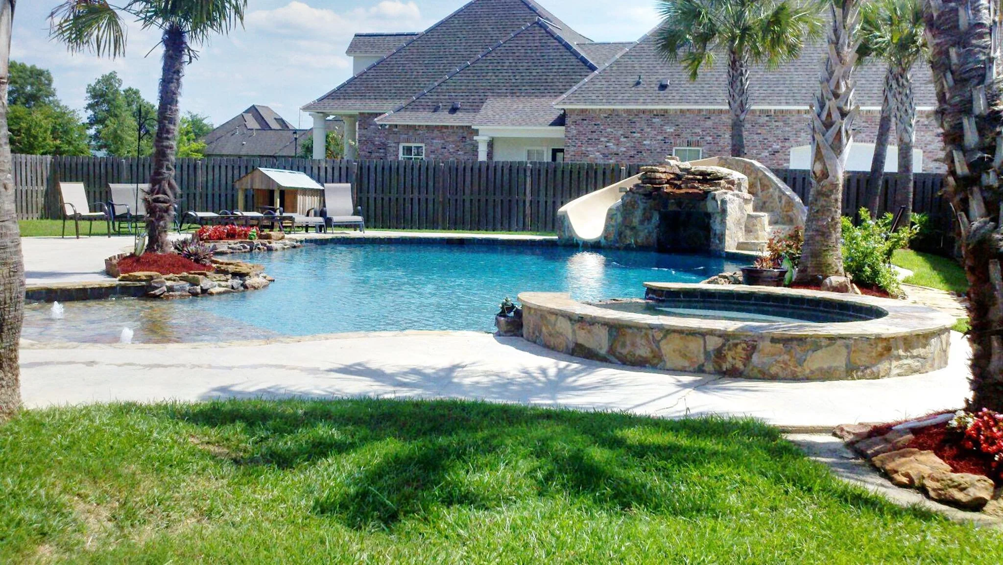 Custom-designed freeform residential pool with rock waterfall, waterslide, hot tub, zero entry in Baton Rouge built by Gulf South Pools & Outdoors.