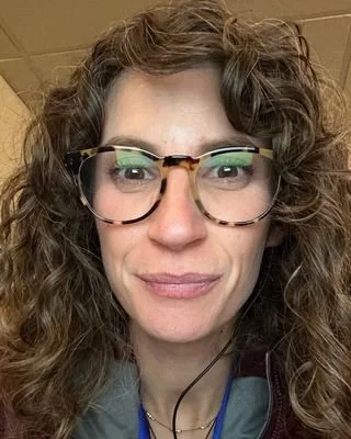 woman with brown curly hair and glasses