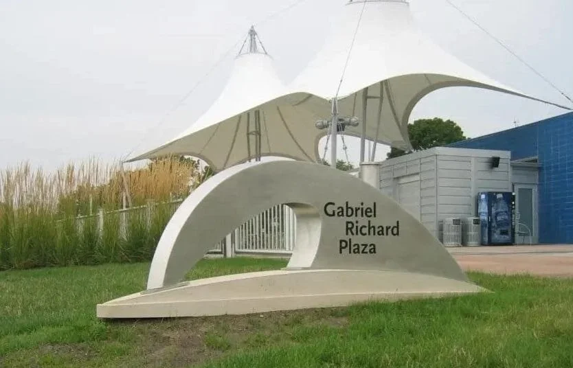 Construction workers installing soundproof panels on a dark wall in a modern office. One worker touches the panel, another discusses, a third moves nearby. A tripod with equipment is on a table in the foreground.