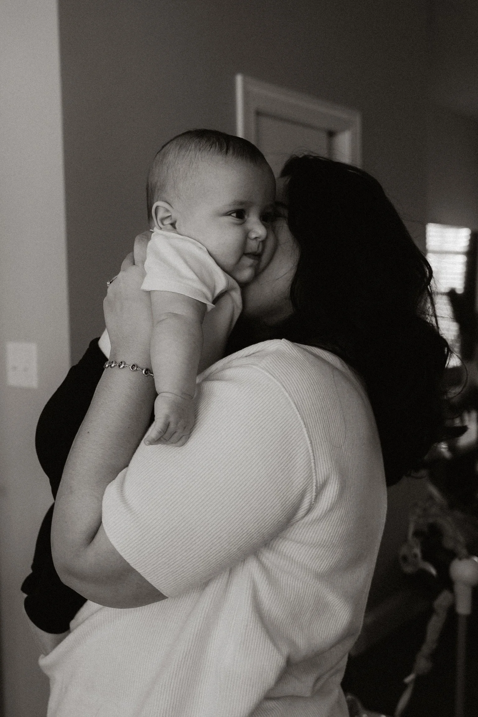 A woman holding a child close to her face, sharing a kiss in a home setting.