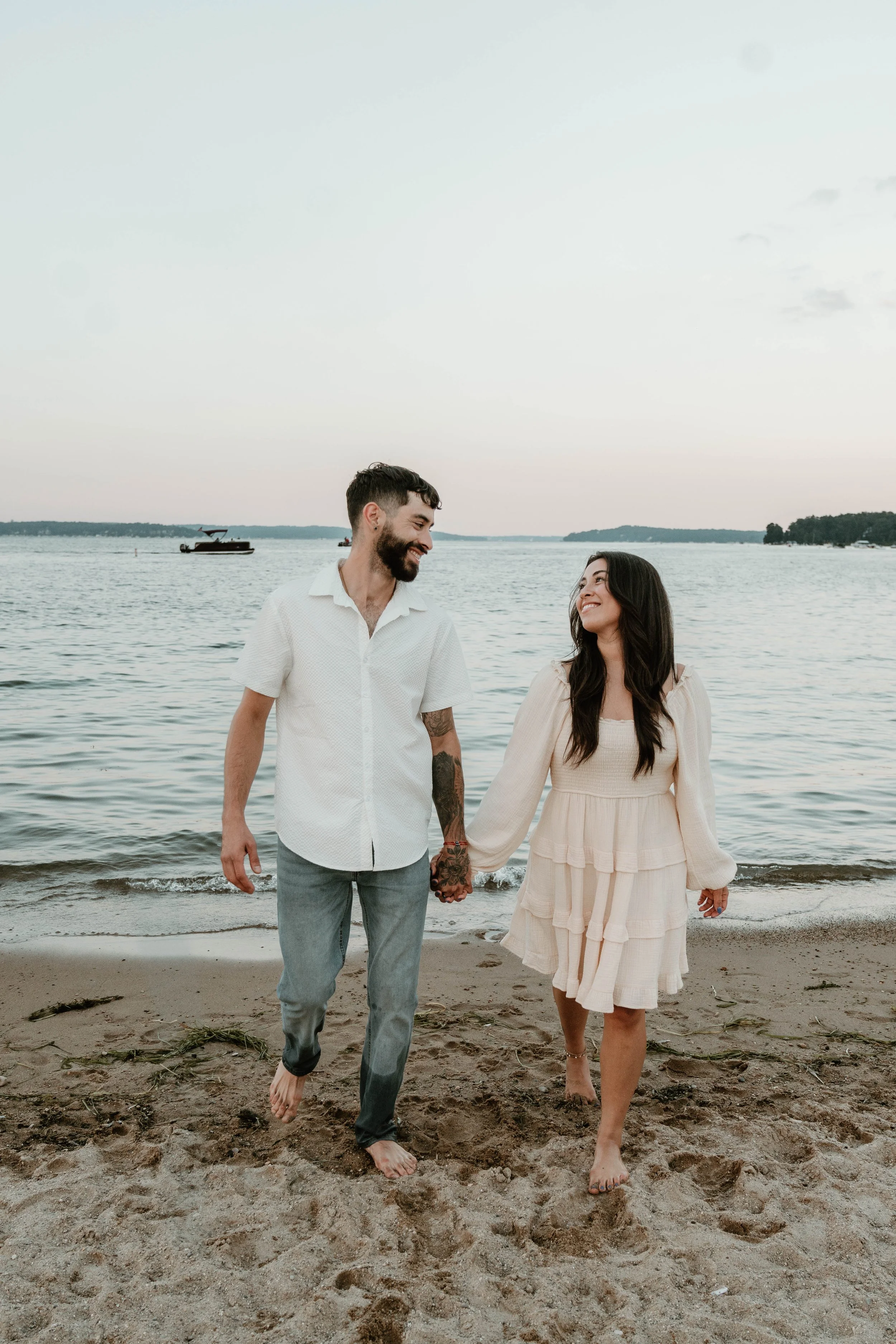 A couple holding hands and walking on a beach.