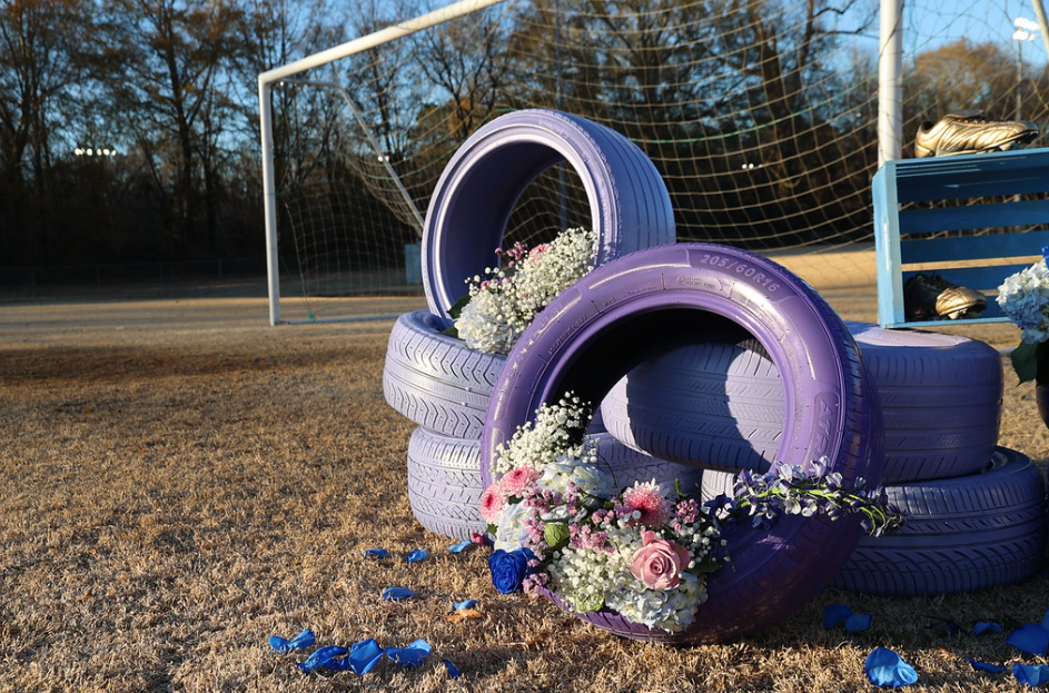 Sports field goal with decorative purple tires filled with flowers in front of it.