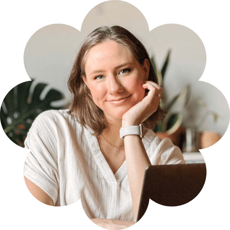 Smiling Erin Payne with hand on chin in front of laptop