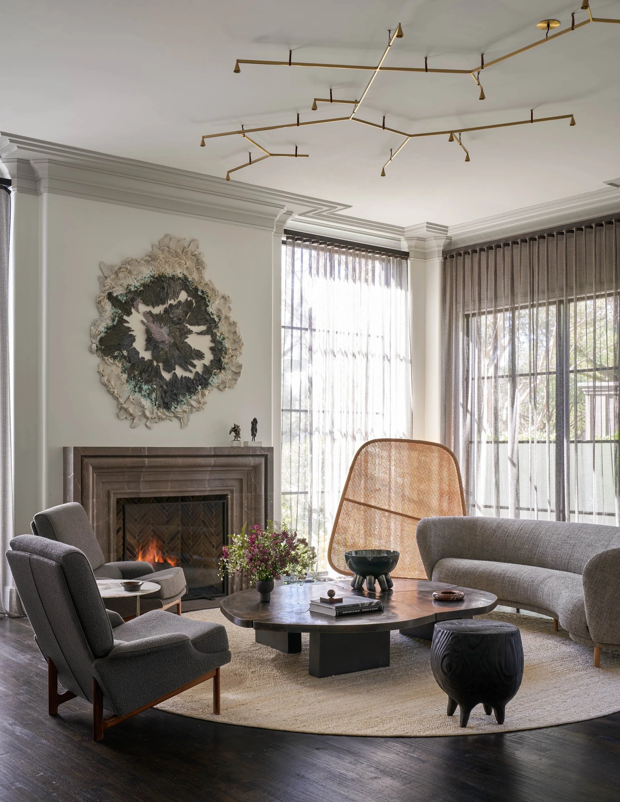 Luxury modern living room interior design by Joshua Rice Design featuring sculptural chandelier and stone fireplace