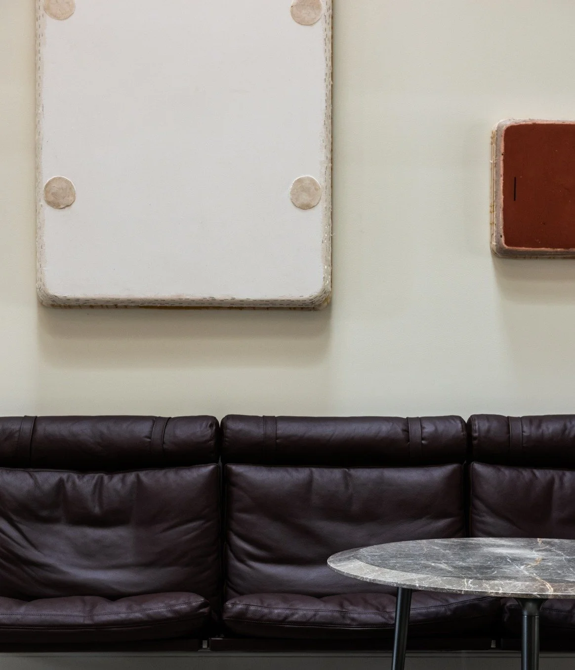 Elegant interior seating vignette with leather bench, marble side table, and contemporary wall sculpture otis jones artist fabricius kastholm wall mount sofa