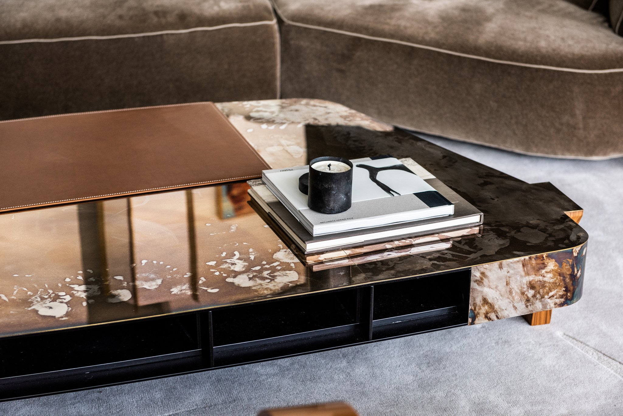 Luxury modern coffee table with sculptural metal surface silvered brass, leather desk pad, and curated design books in contemporary living room. vincenzo de cotiis , progetto domestico, rick owens, mad et lin candle.  mohair sofa