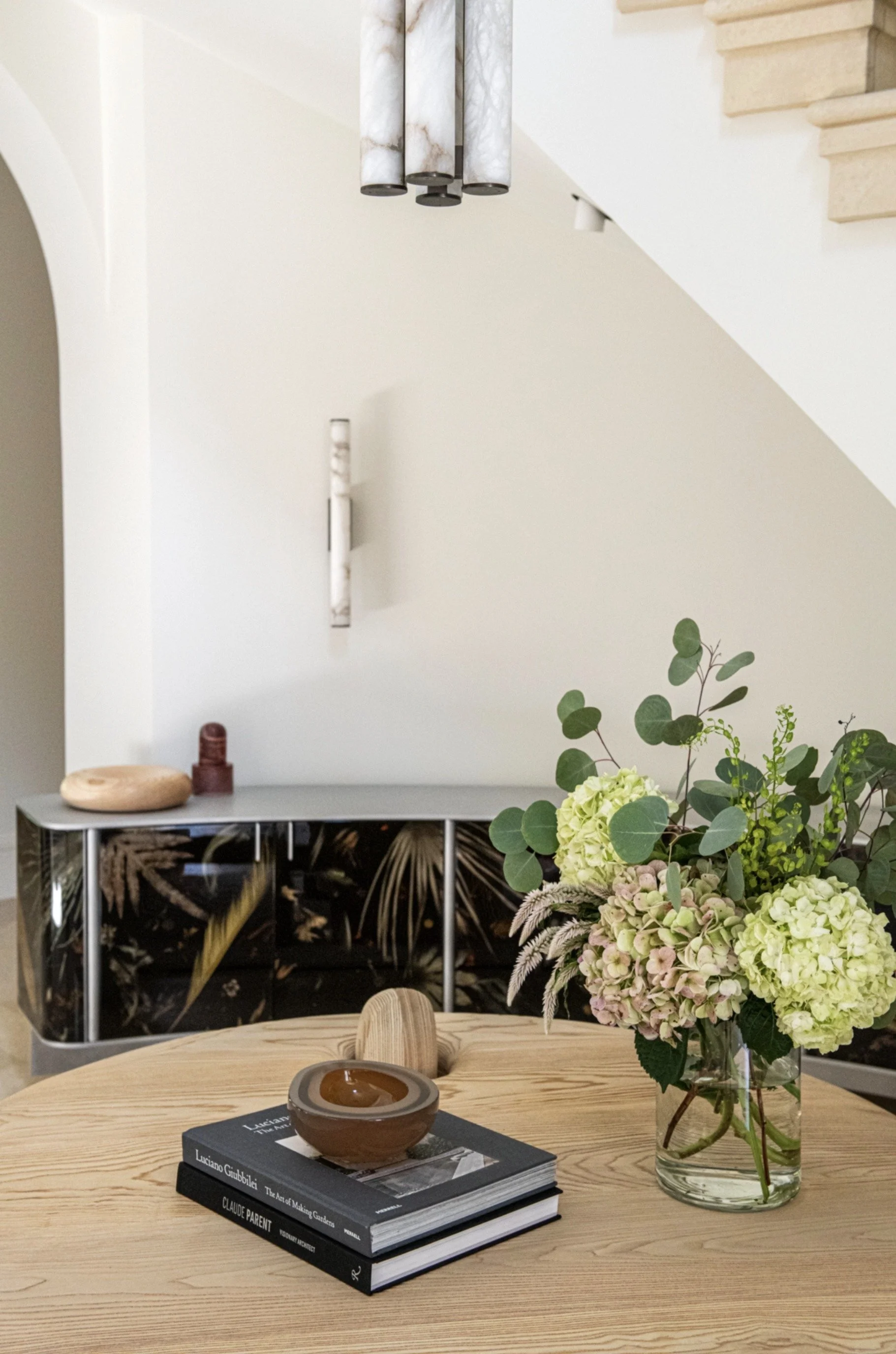 A softly lit entry hall balances architectural calm with collected detail. A custom console by Marcin Rusak and table by Casey McCafferty, alabaster lighting, and restrained floral arrangement create an understated but memorable first impression.