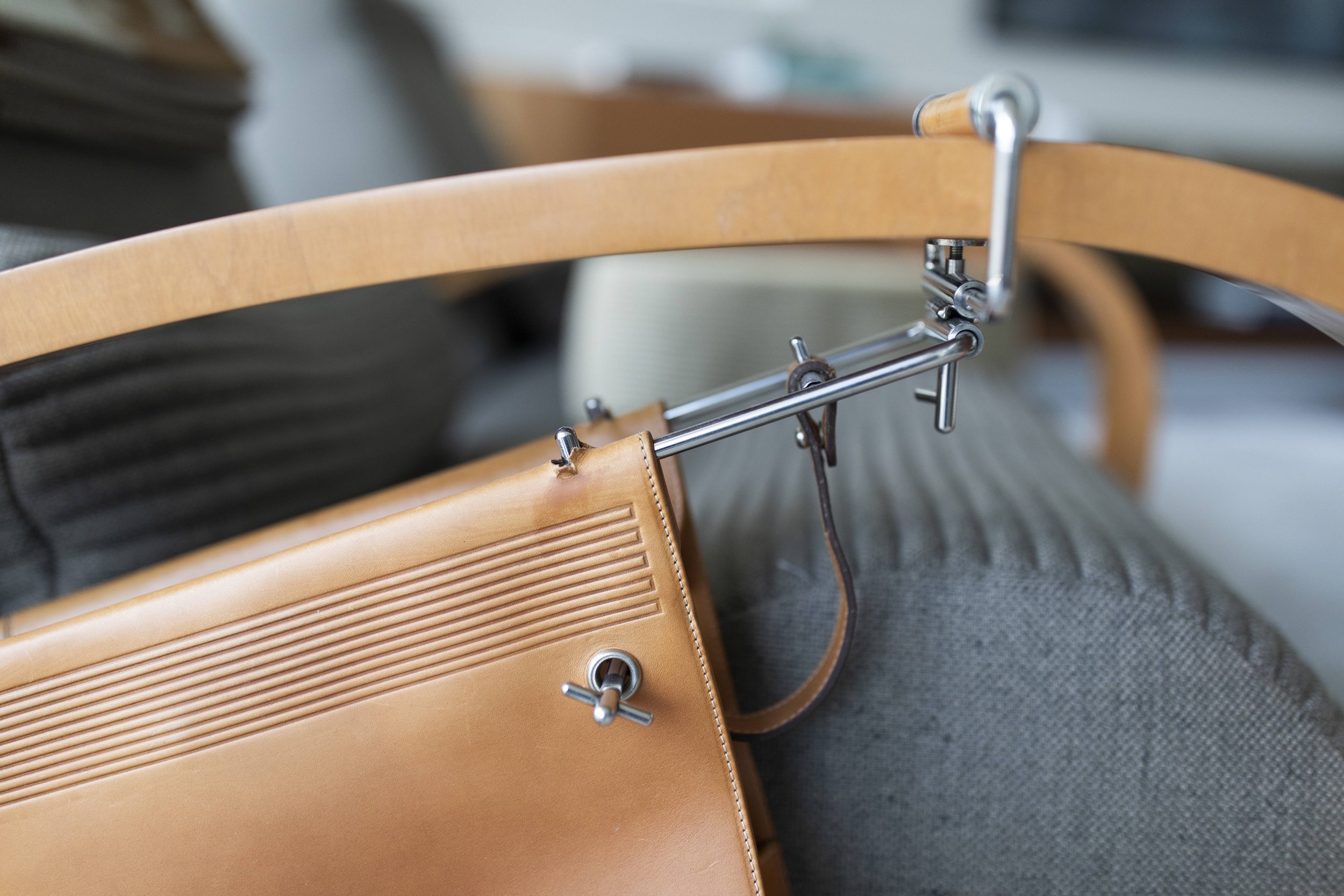 Luxury lounge chair with curved wood frame and leather accessories in modern residential interior design jaime tresserra collection details