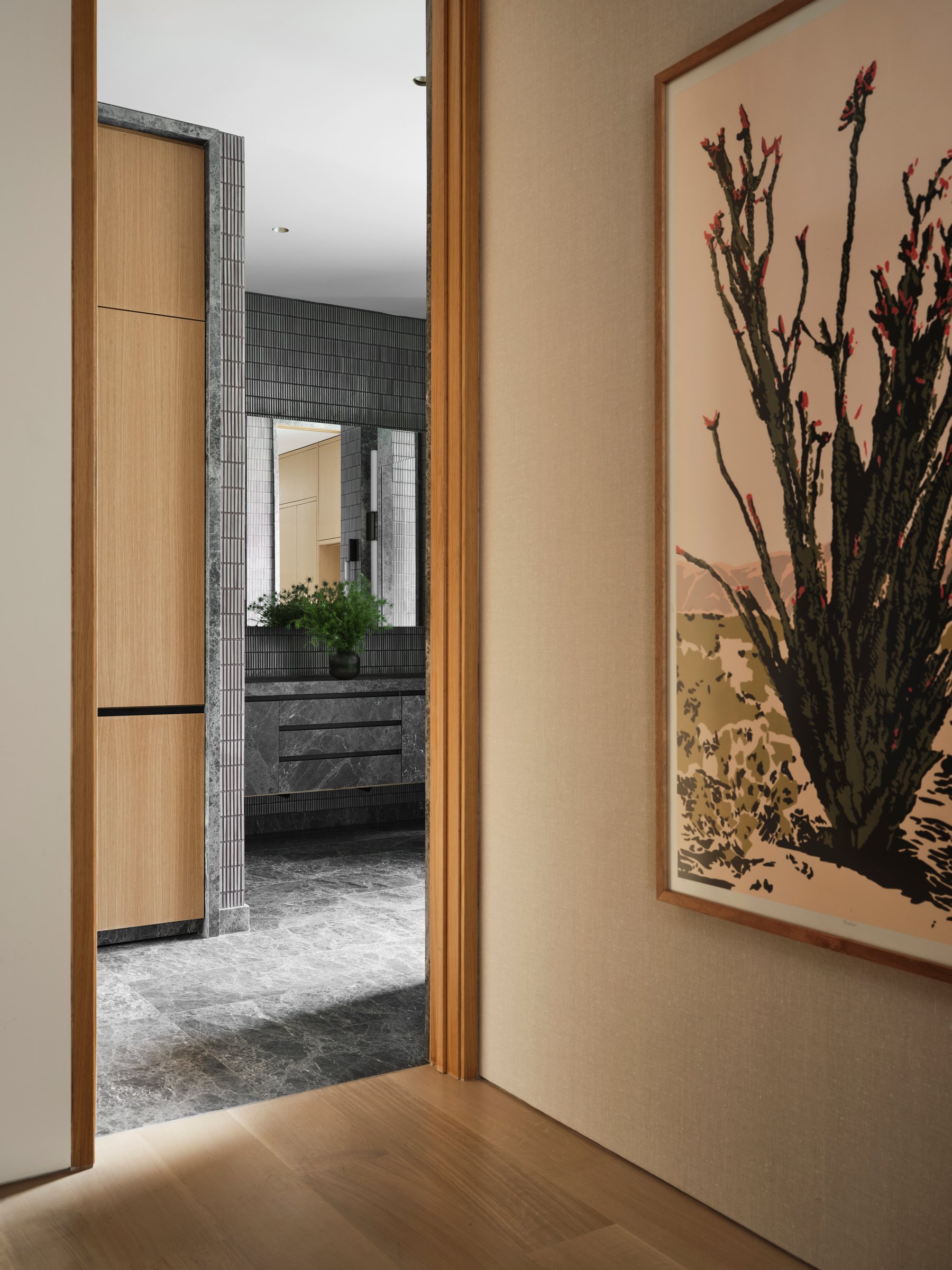 Framed view from corridor into bath, layering stone, tile, and millwork to establish depth and controlled spatial transition.