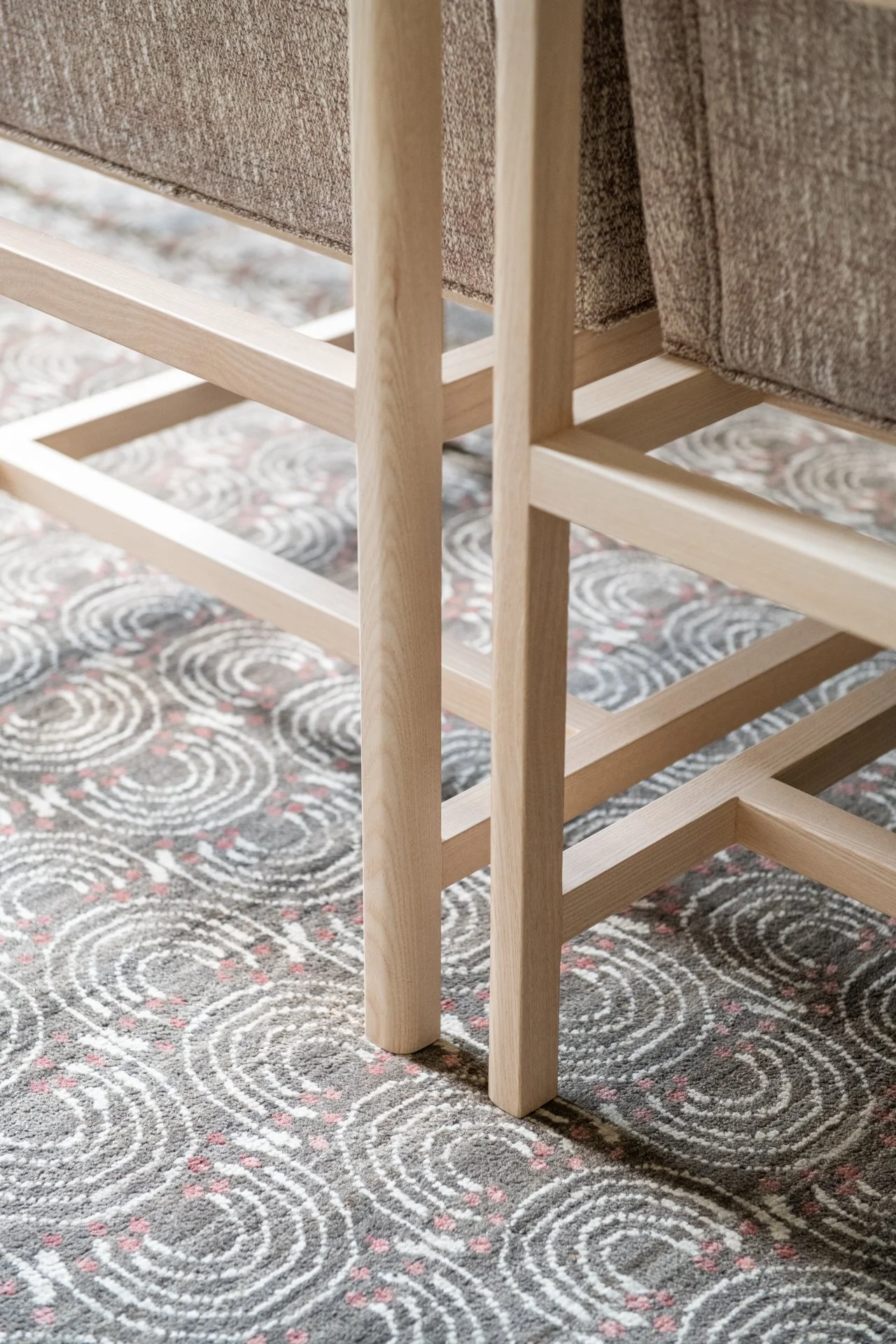 Upholstered dining chairs with pale wood frames by Bassam Fellows on a custom luxury rug.