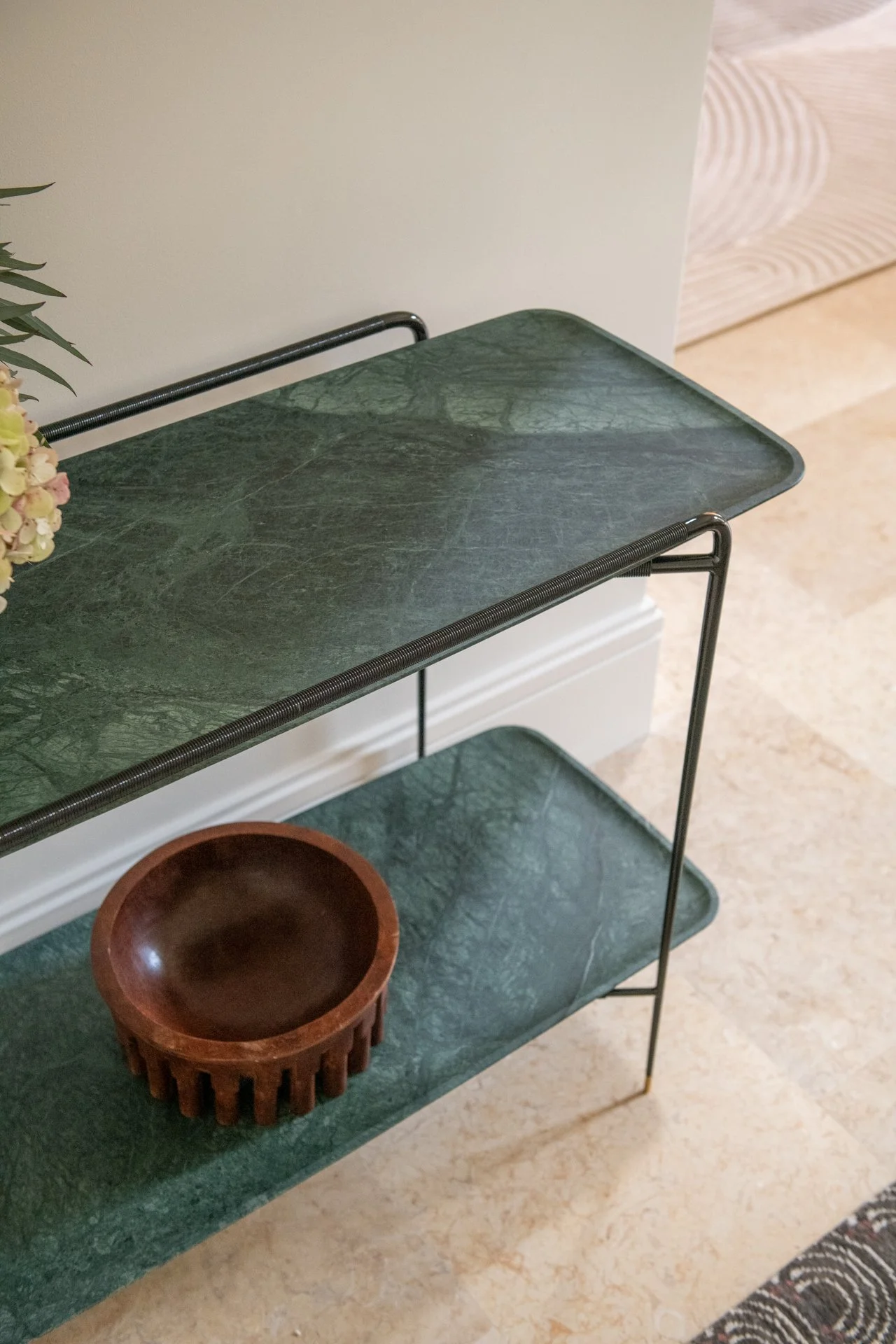 A refined console in deep green stone and darkened metal by jader almeida introduces quiet sculptural presence to the entry. Minimal detailing and rich material contrast create a restrained but memorable architectural moment.
