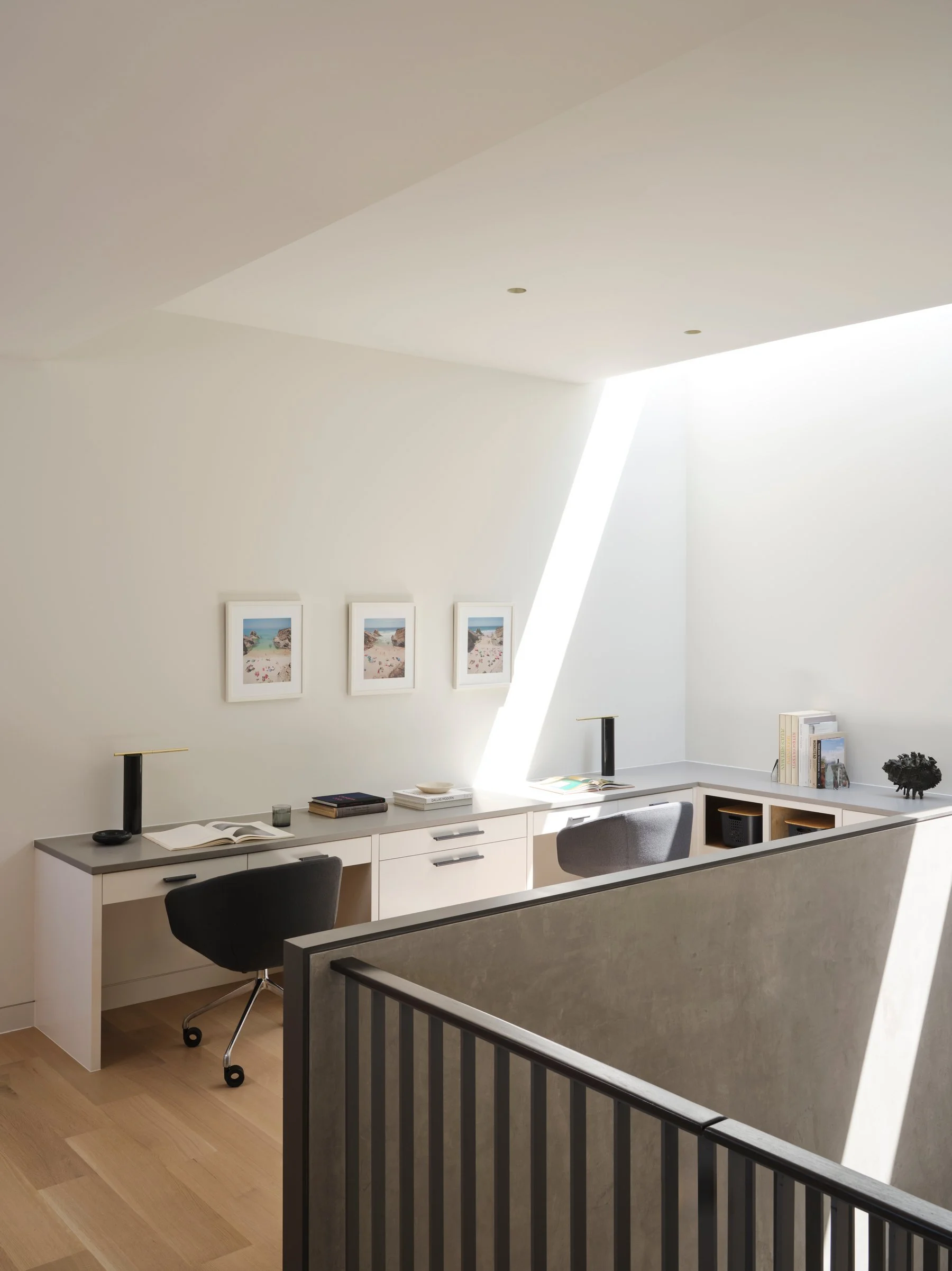 Upper-level workspace with built-in desks and controlled daylight, emphasizing clarity, function, and architectural restraint.