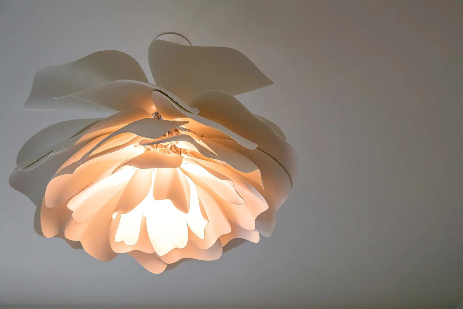Sculptural porcelain pendant light with layered organic petals creating soft ambient lighting in a sophisticated modern luxury residence.