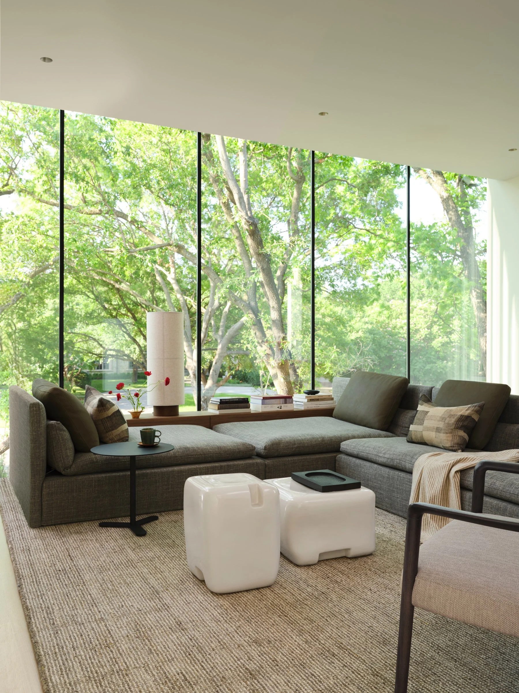 Minimal living room with custom sectional, floor-to-ceiling windows, and soft natural light, creating a calm contemporary interior.