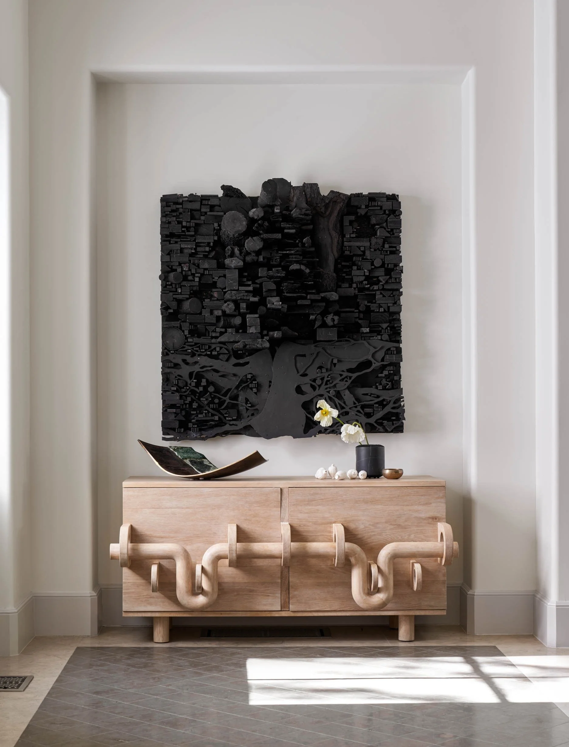 Modern luxury entry console with custom oak cabinet and large contemporary black wall sculpture Leonardo Drew Art