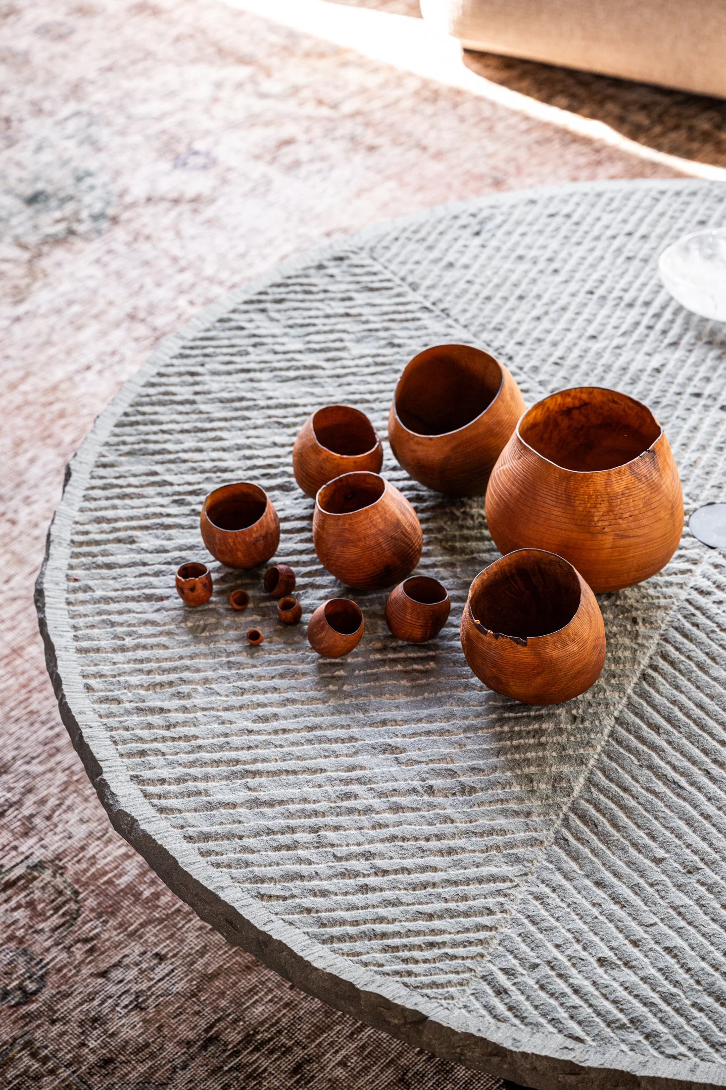 Carved stone coffee table with hand-turned wood vessels, highlighting natural materials and sculptural objects in a contemporary living space. Vintage and Rare Stone Coffee Table Designed by architect Giulio Lazzotti Produced by Mageia in Italy, ca. 