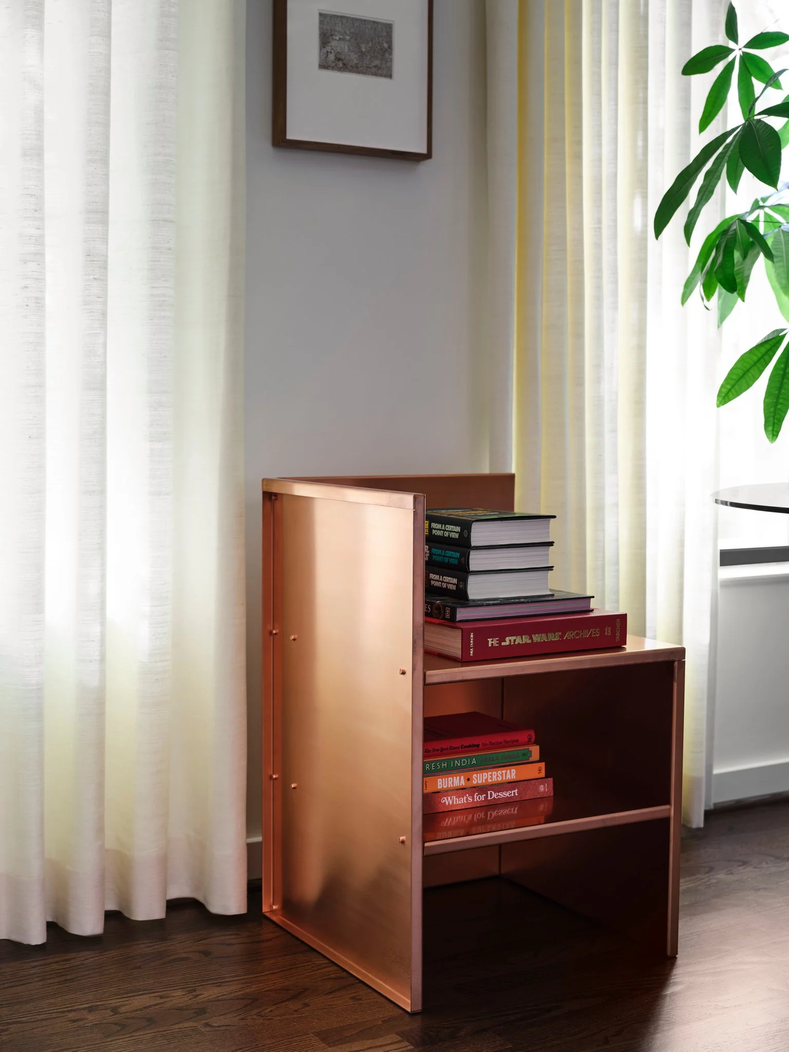 Classic chair by Donald Judd in warm copper finish styled with books, set against linen drapery in a modern residential interior.