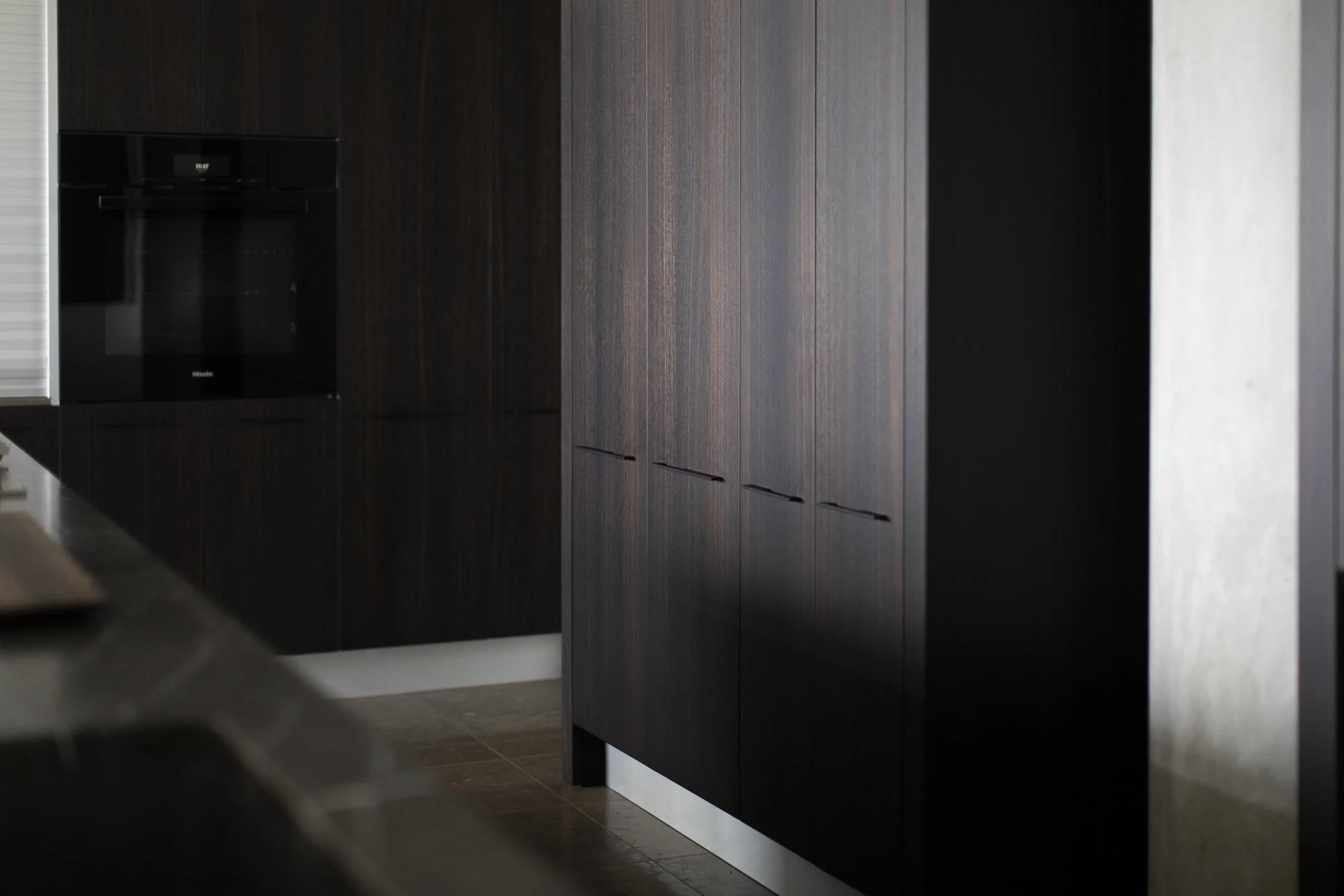 Modern luxury kitchen cabinetry with dark wood finish and integrated appliances poliform wolf oven, grey marble